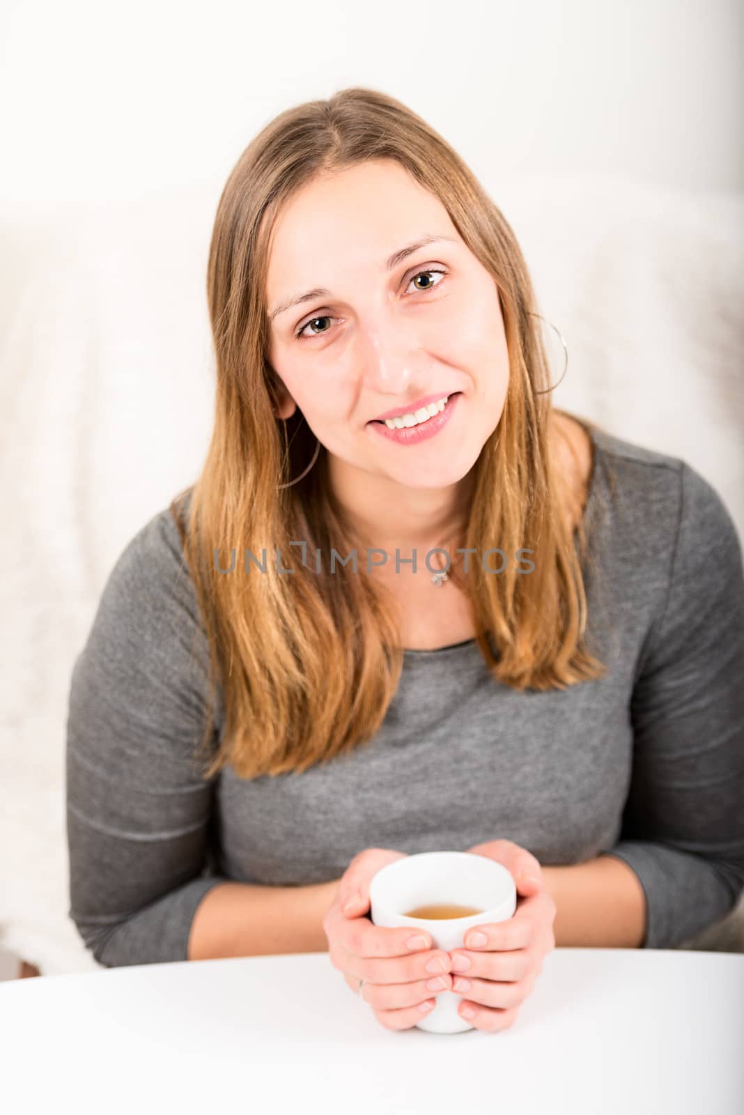 Happy girl in grey holding mug front view by Nanisimova