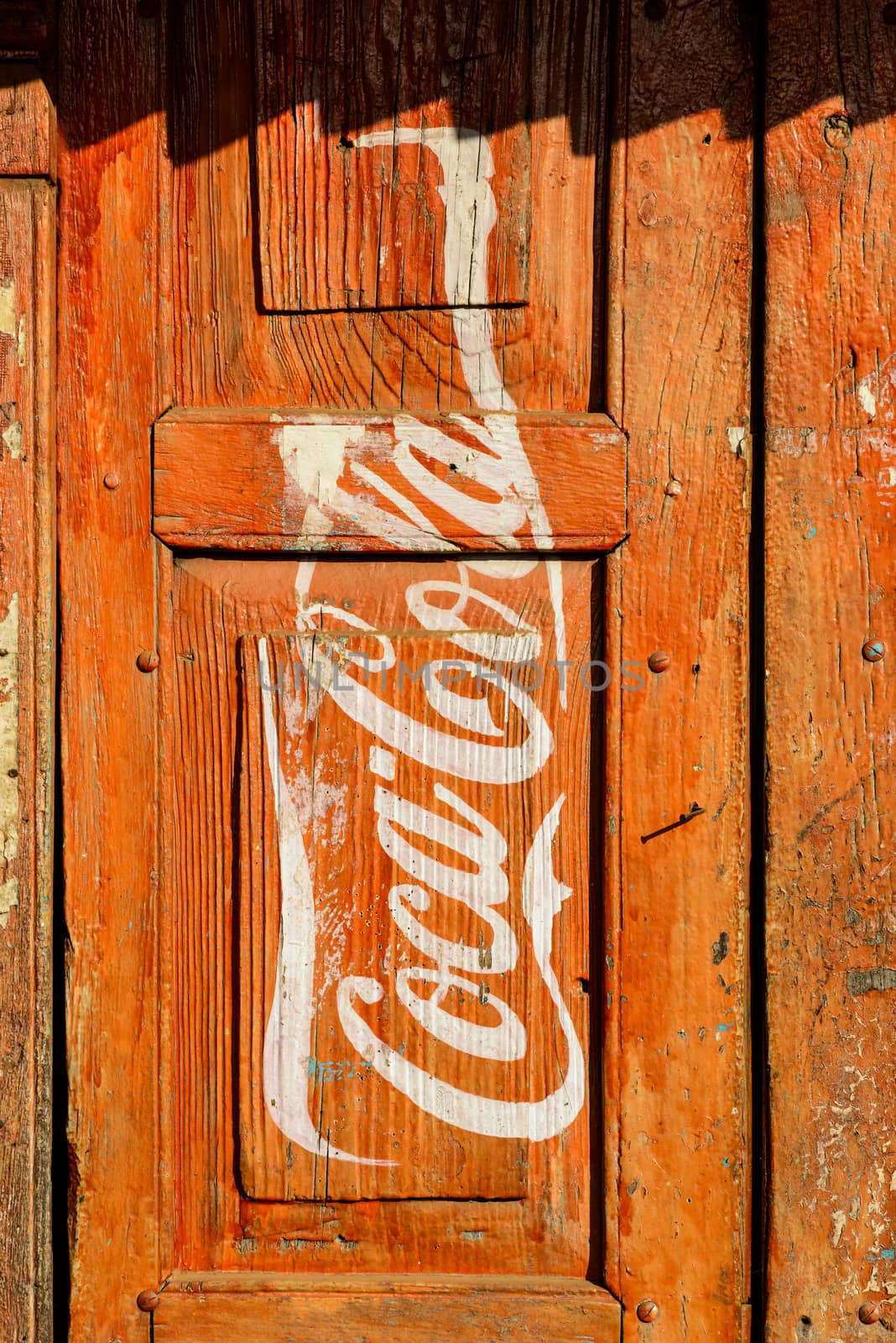 KATHMANDU, NEPAL - CIRCA JANUARY 2014: Vintage Coca-Cola adverisement painted on a red wooden door.