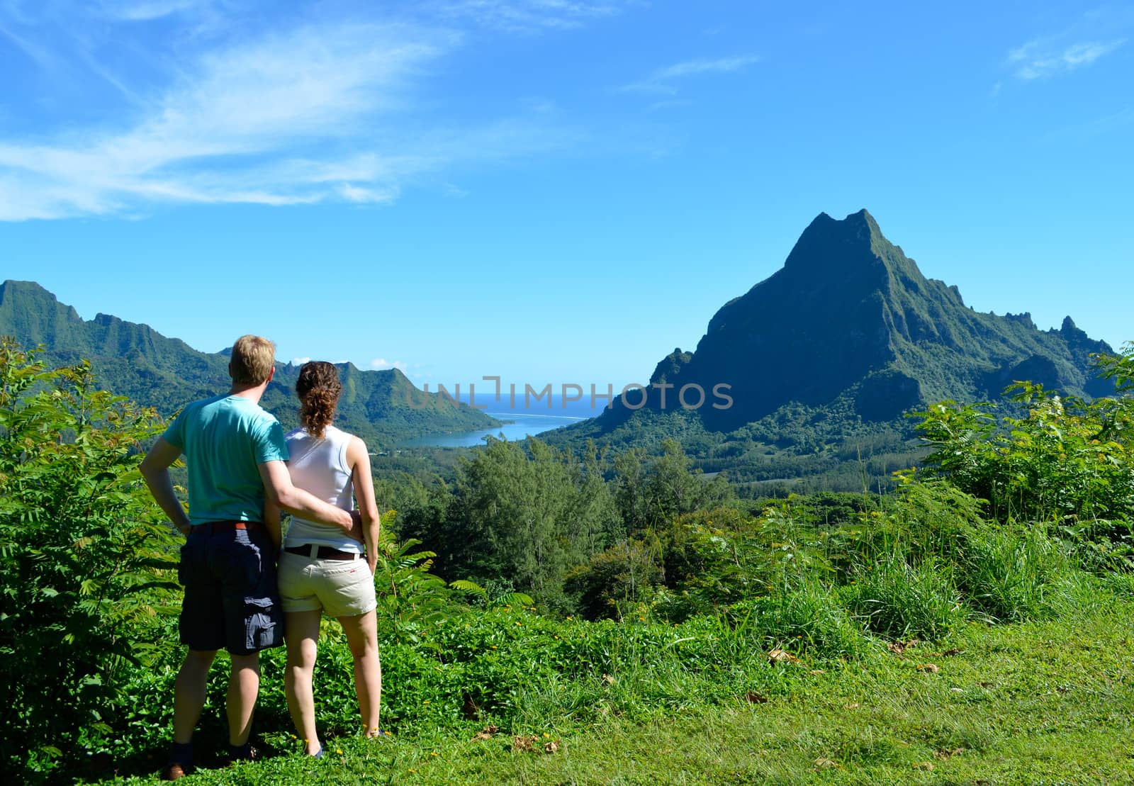 Young honeymoon couple with an overview over Rotui mountain and Opunohu Bay on the tropical pacific island of Moorea, near Tahiti in French Polynesia.