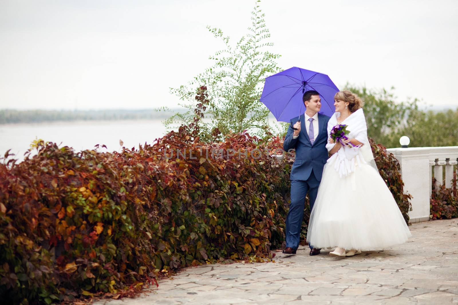 bride and groom walking under umbrella