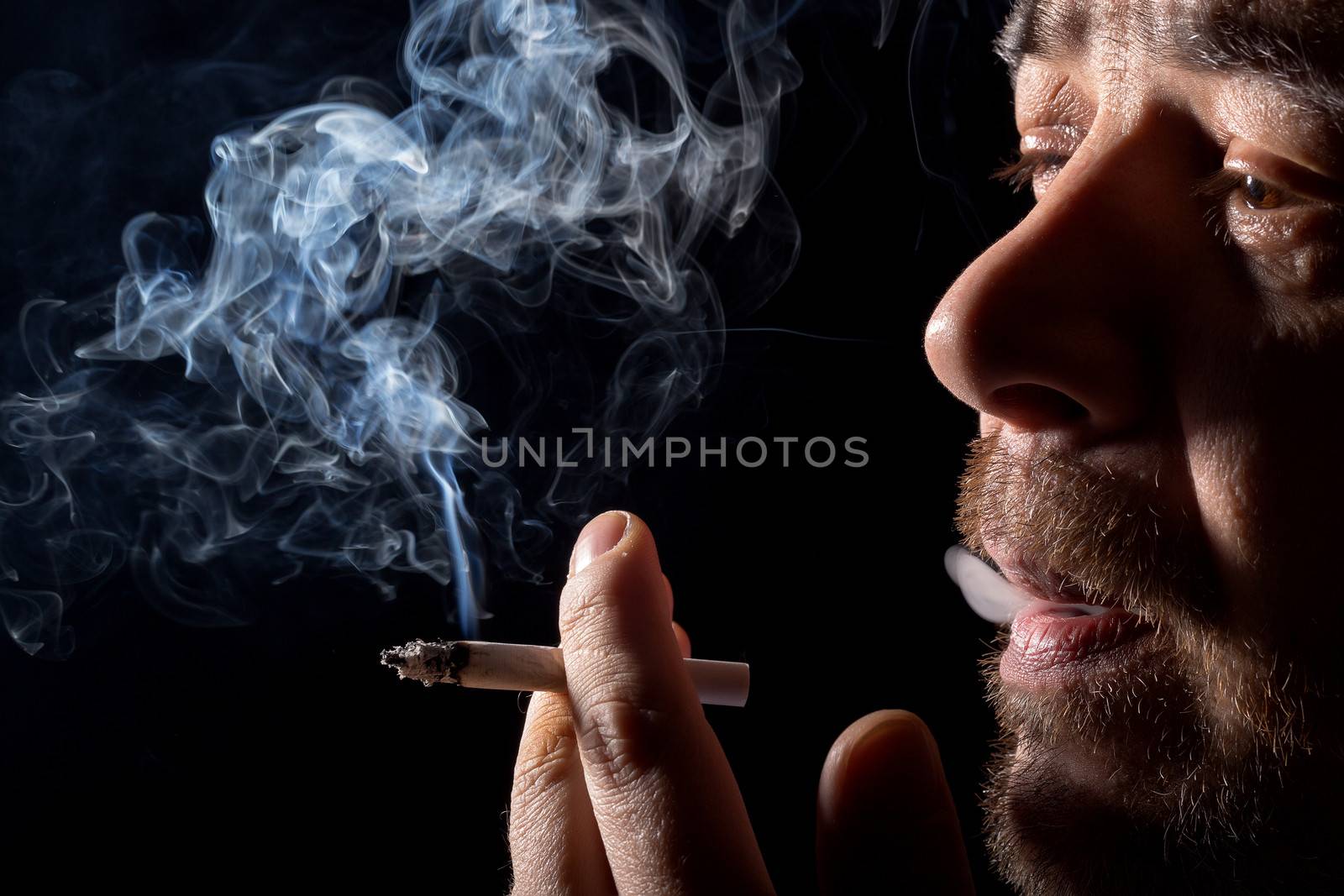 Portrait man smoking cigarette, closeup on black background