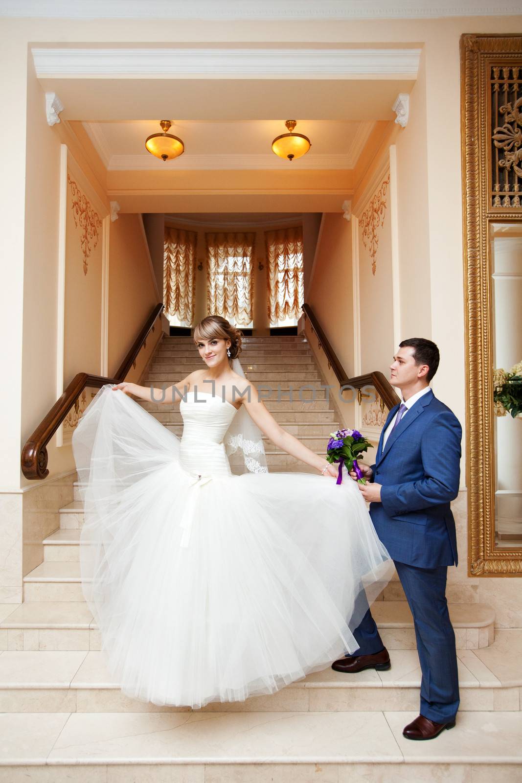 groom and bride in hall with staircase