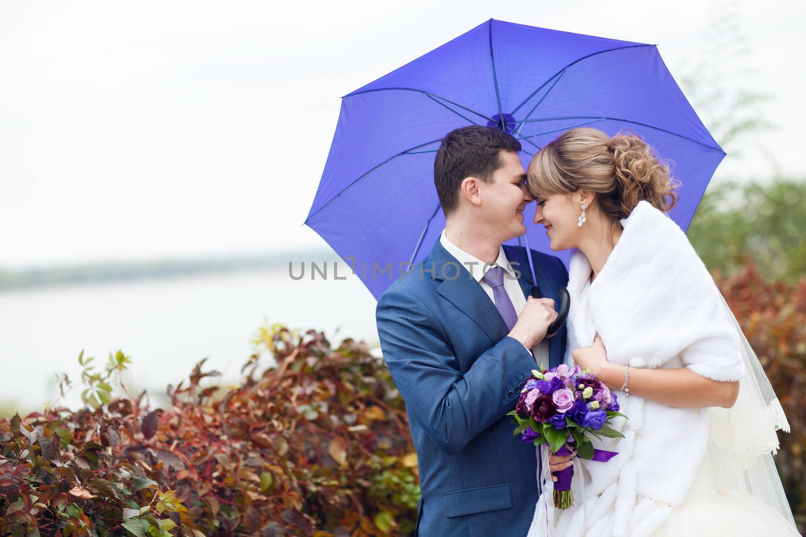 bride and groom under umbrella by vsurkov