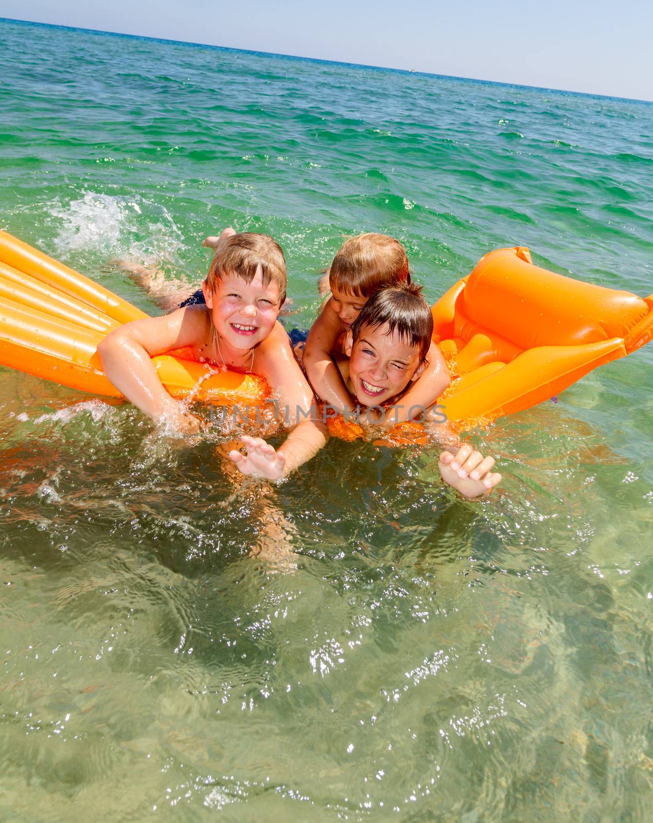Three kids enjoying summer day floating in the sea