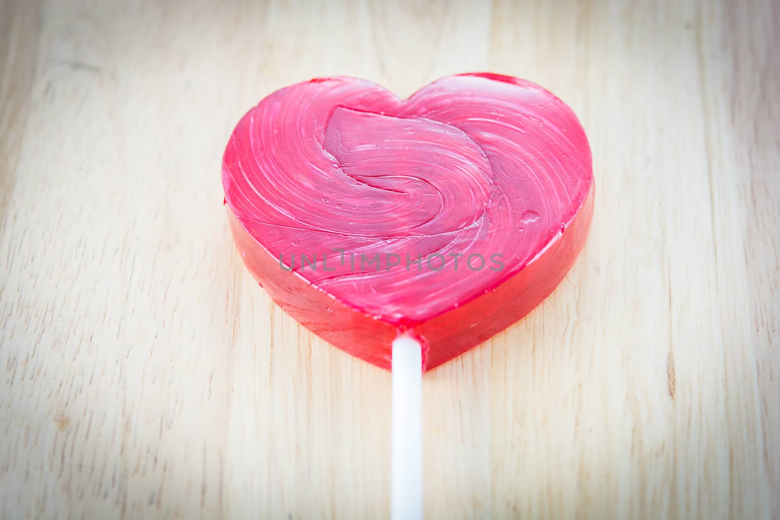 Heart shaped colorful lollipop on wooden background