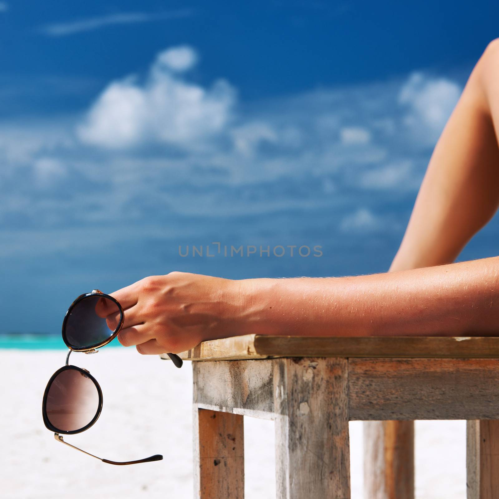 Woman at beach holding sunglasses by haveseen