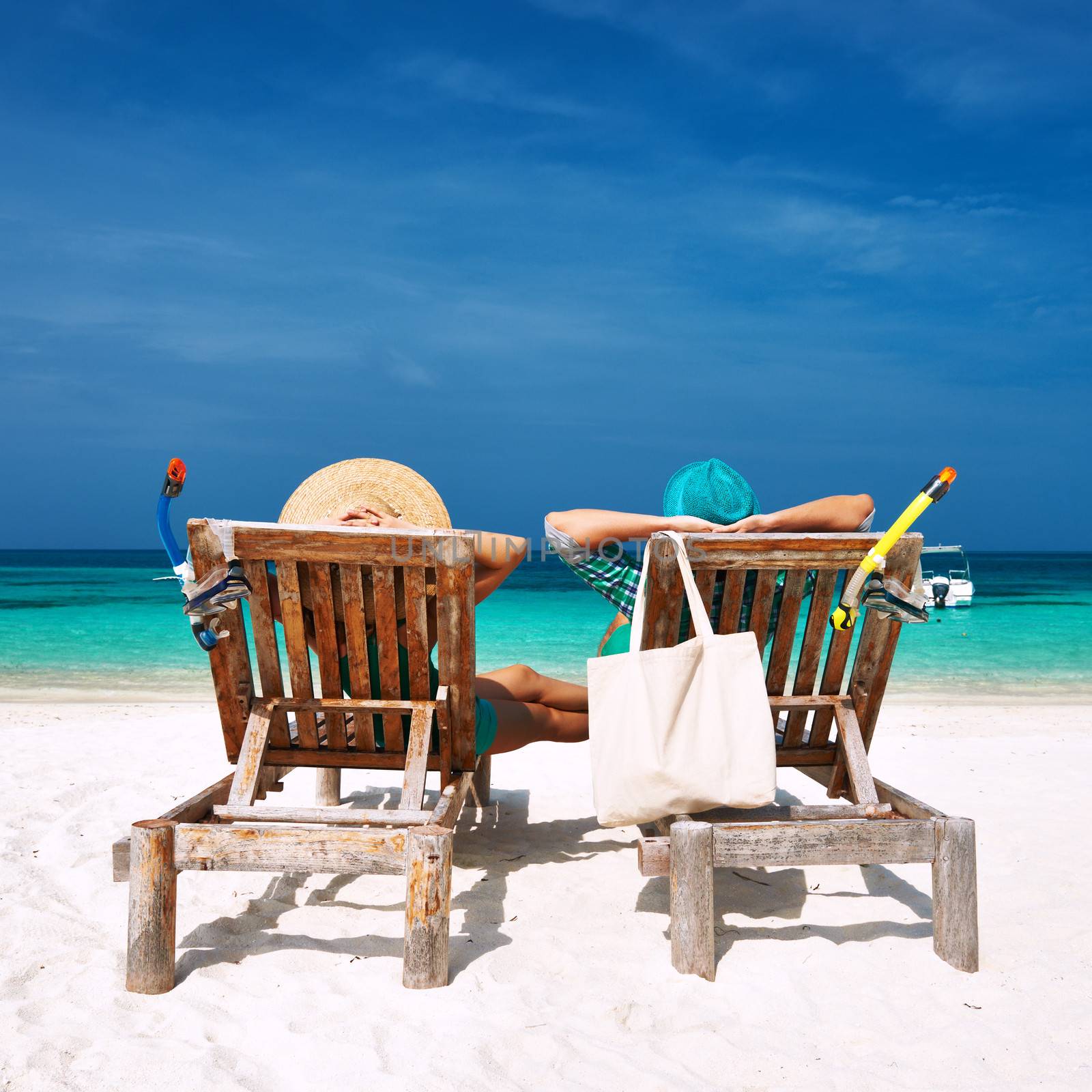 Couple in green relax on a tropical beach at Maldives