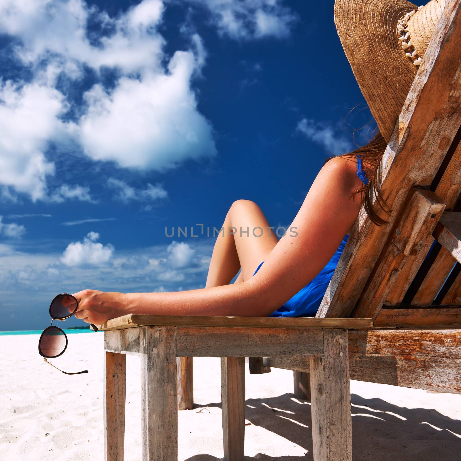 Woman at beach holding sunglasses by haveseen