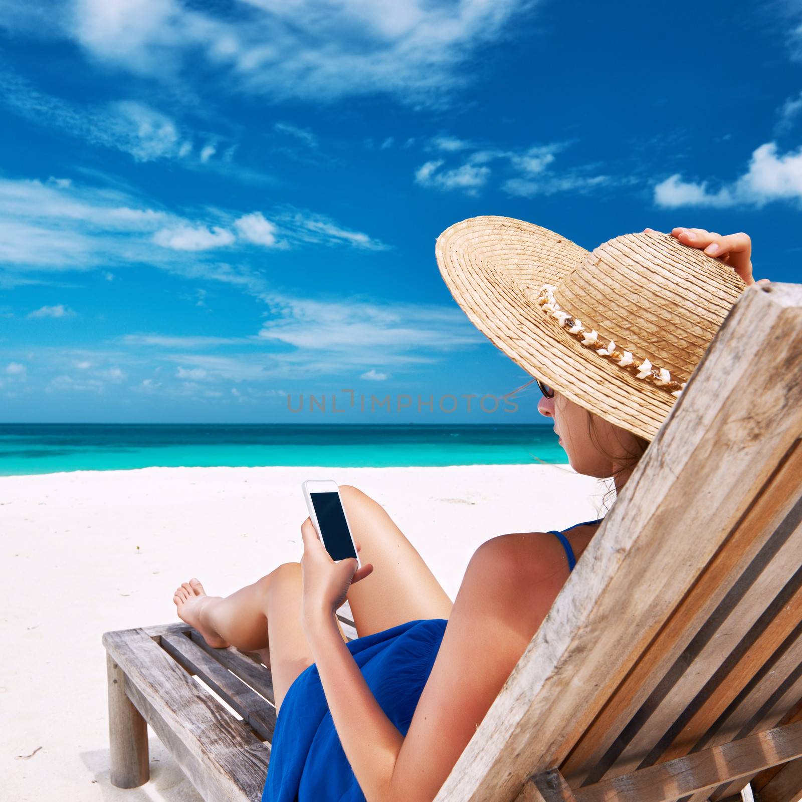 Young woman in hat with mobile phone at the beach