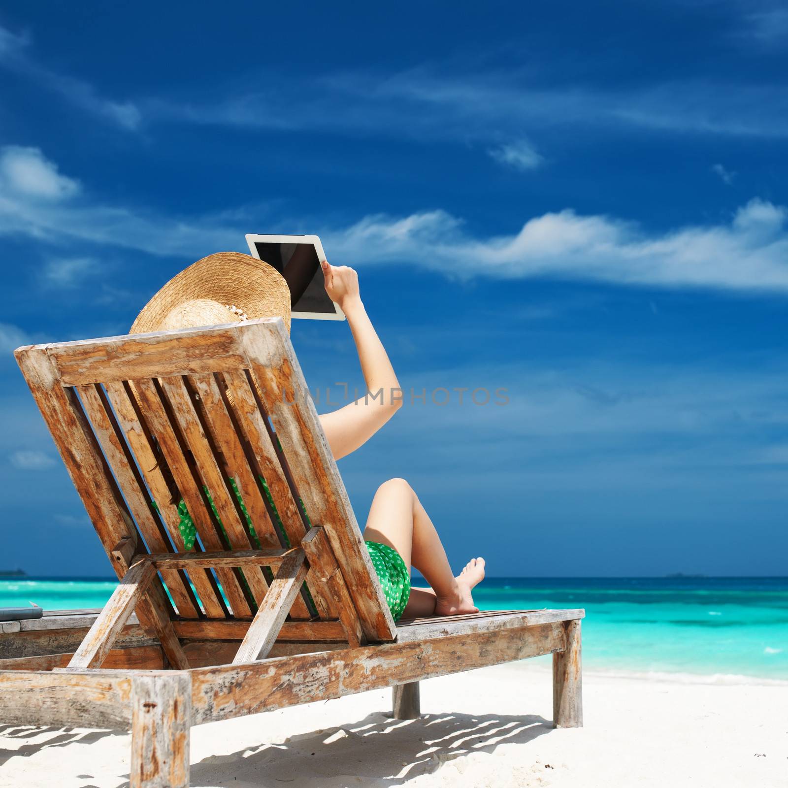 Young woman in hat with tablet pc at the beach