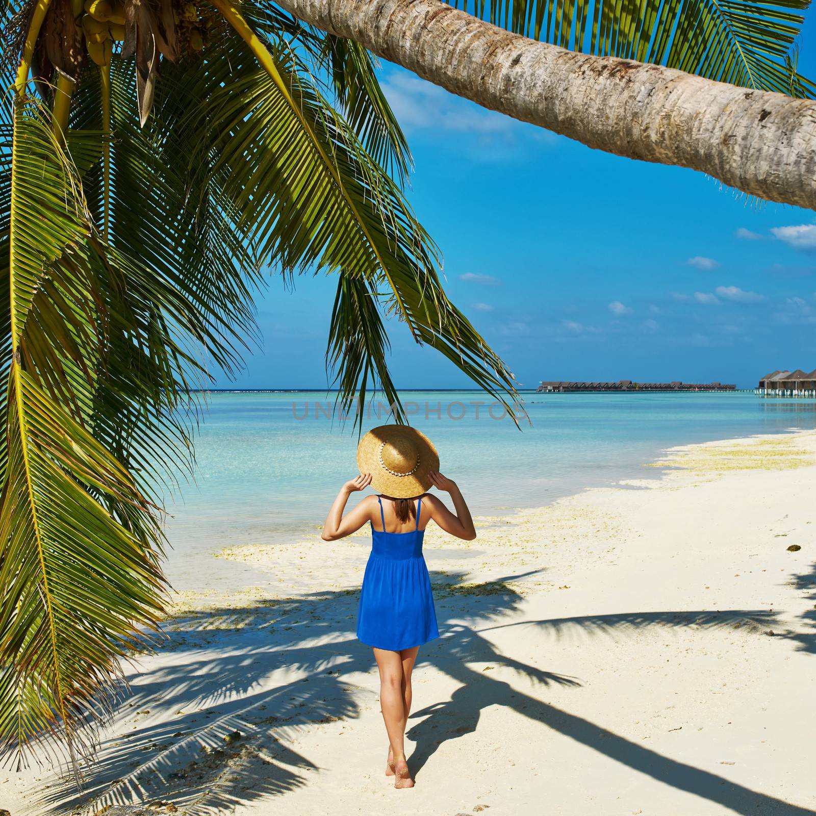 Woman in blue dress on a tropical beach at Maldives