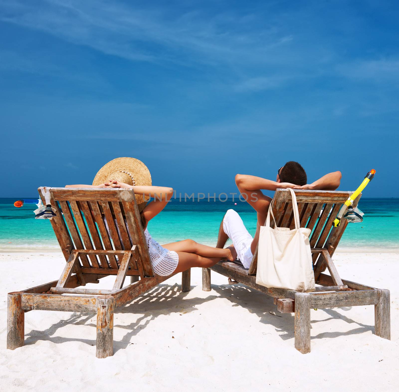 Couple in white relax on a tropical beach at Maldives