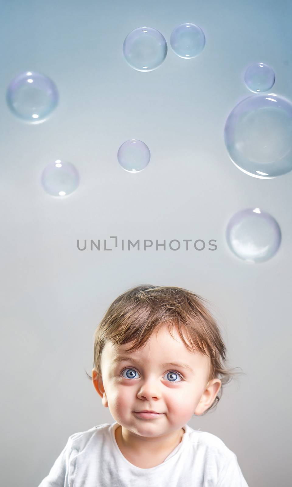 Smiling baby looking up to the bubbles in the air