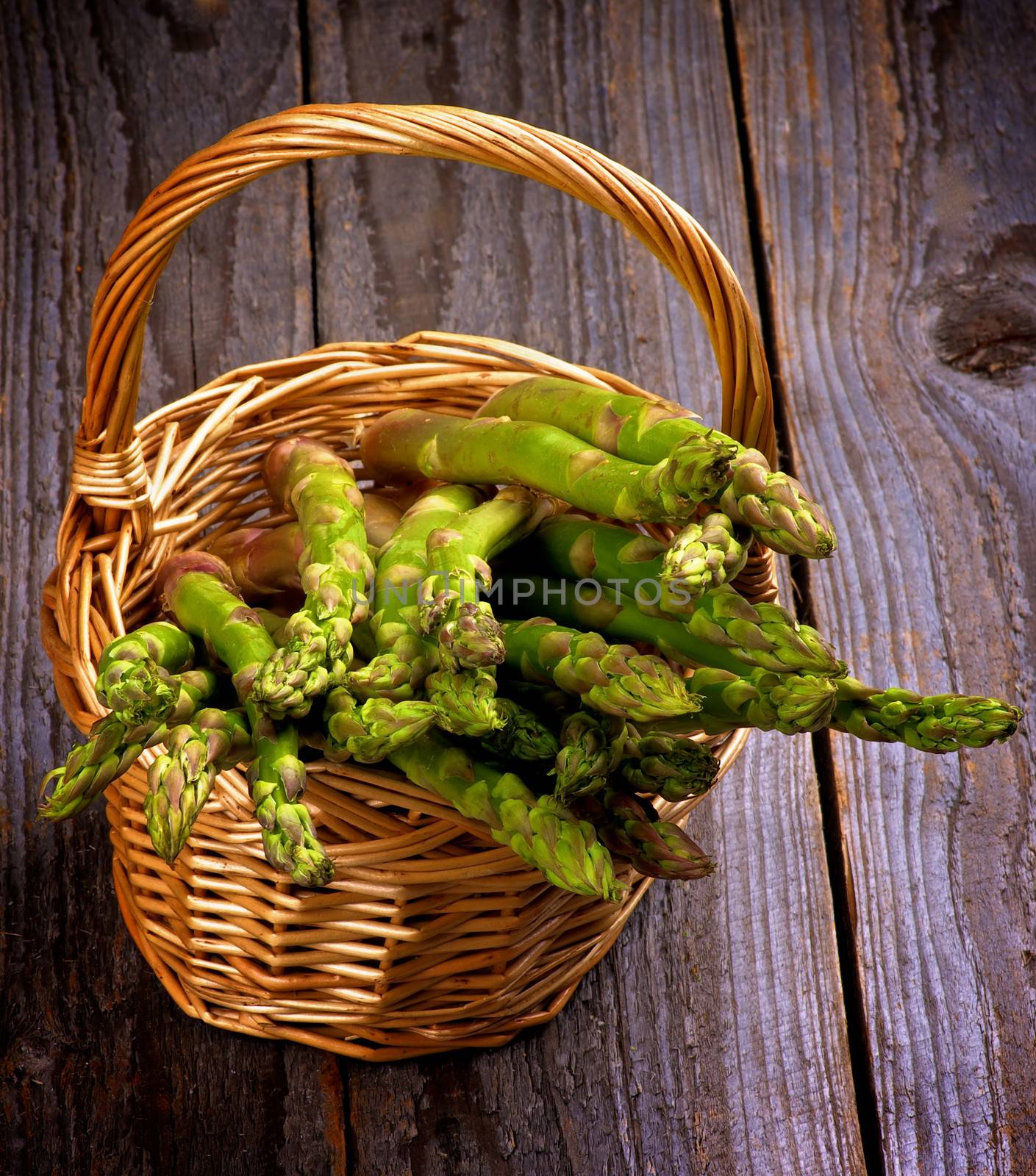Asparagus Sprouts in Wicker Basket isolated on Rustic Wooden background