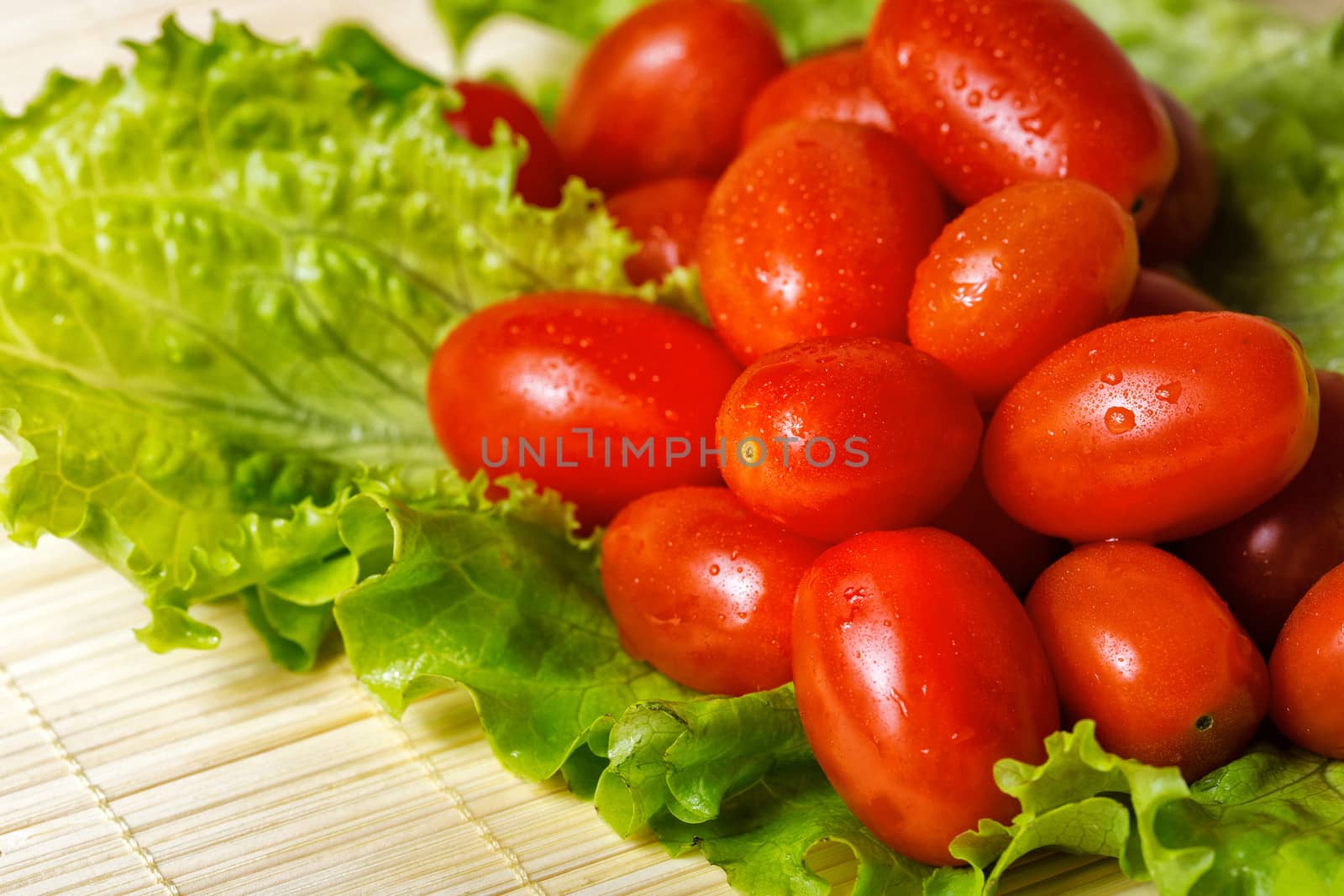 Vegetarian tomato and lettuce on bamboo tray are photographed close-up