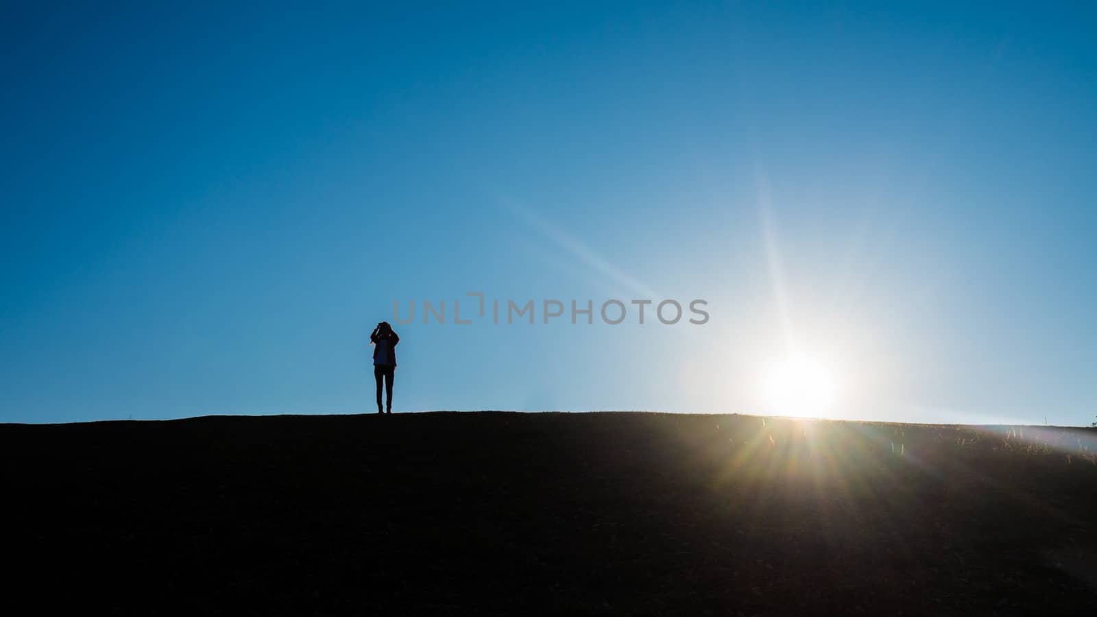 silhouette of people on hill with sunrise and lens flare effect