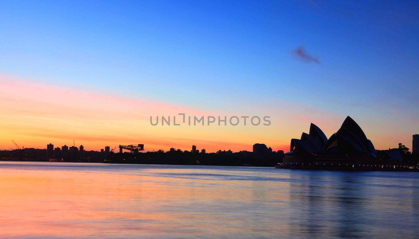 Sydney, Australia - November 28, 2013;  Sunrise at Sydney, with the Sydney Opera House silhouette and reflections on Sydney Harbour