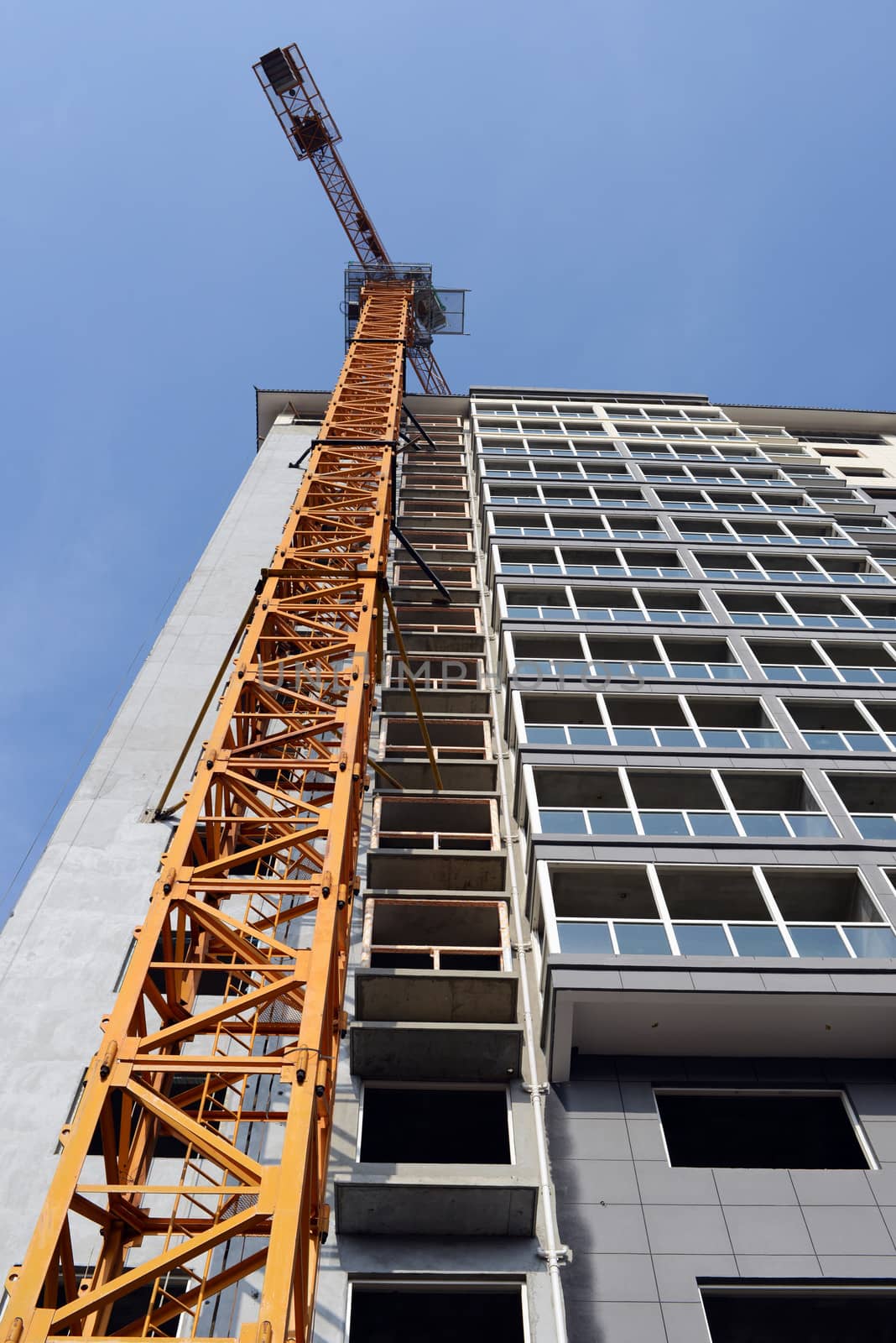 High-rise building under construction, with cranes against blue sky 