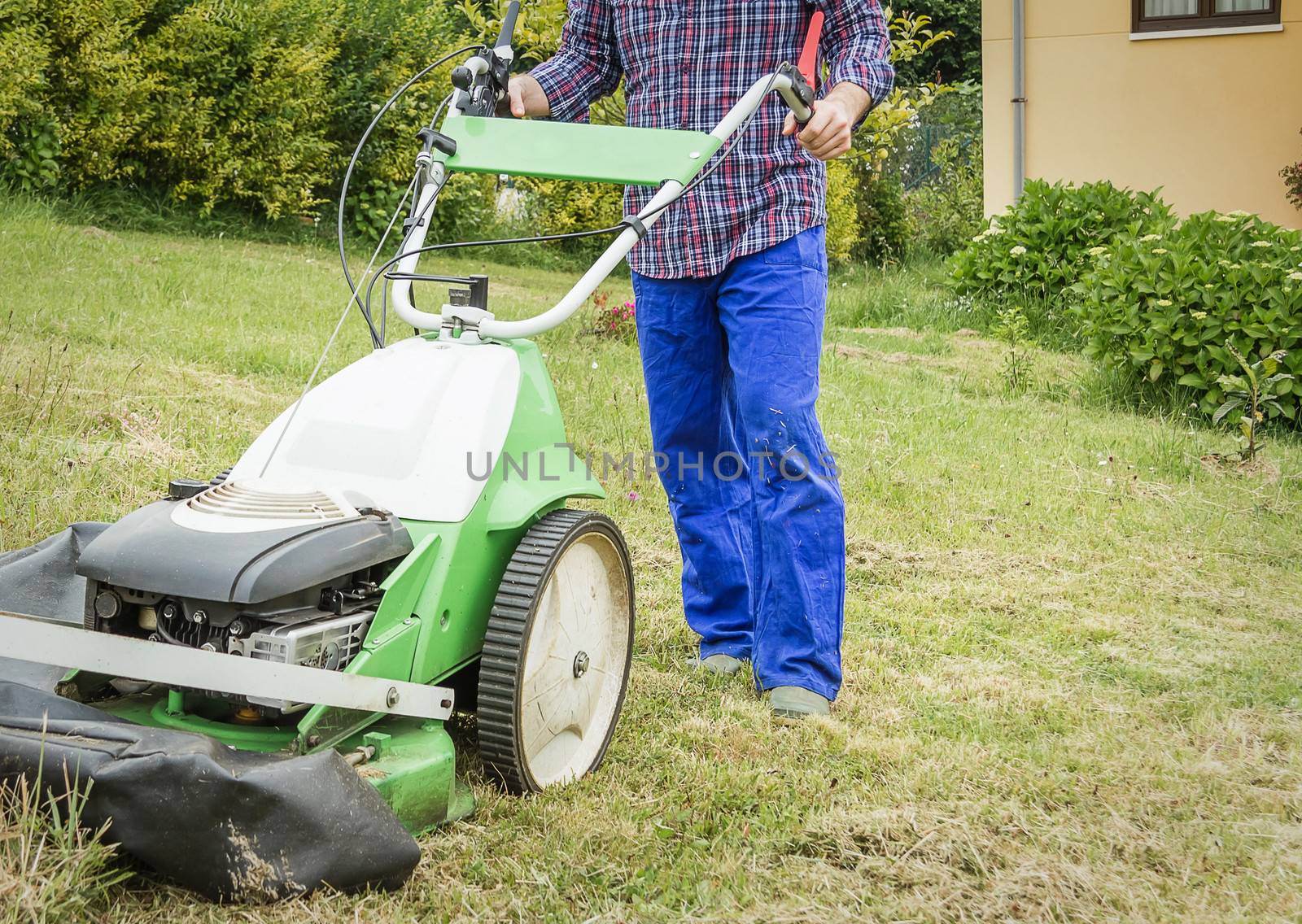 Young man mowing the lawn with a lawnmower machine