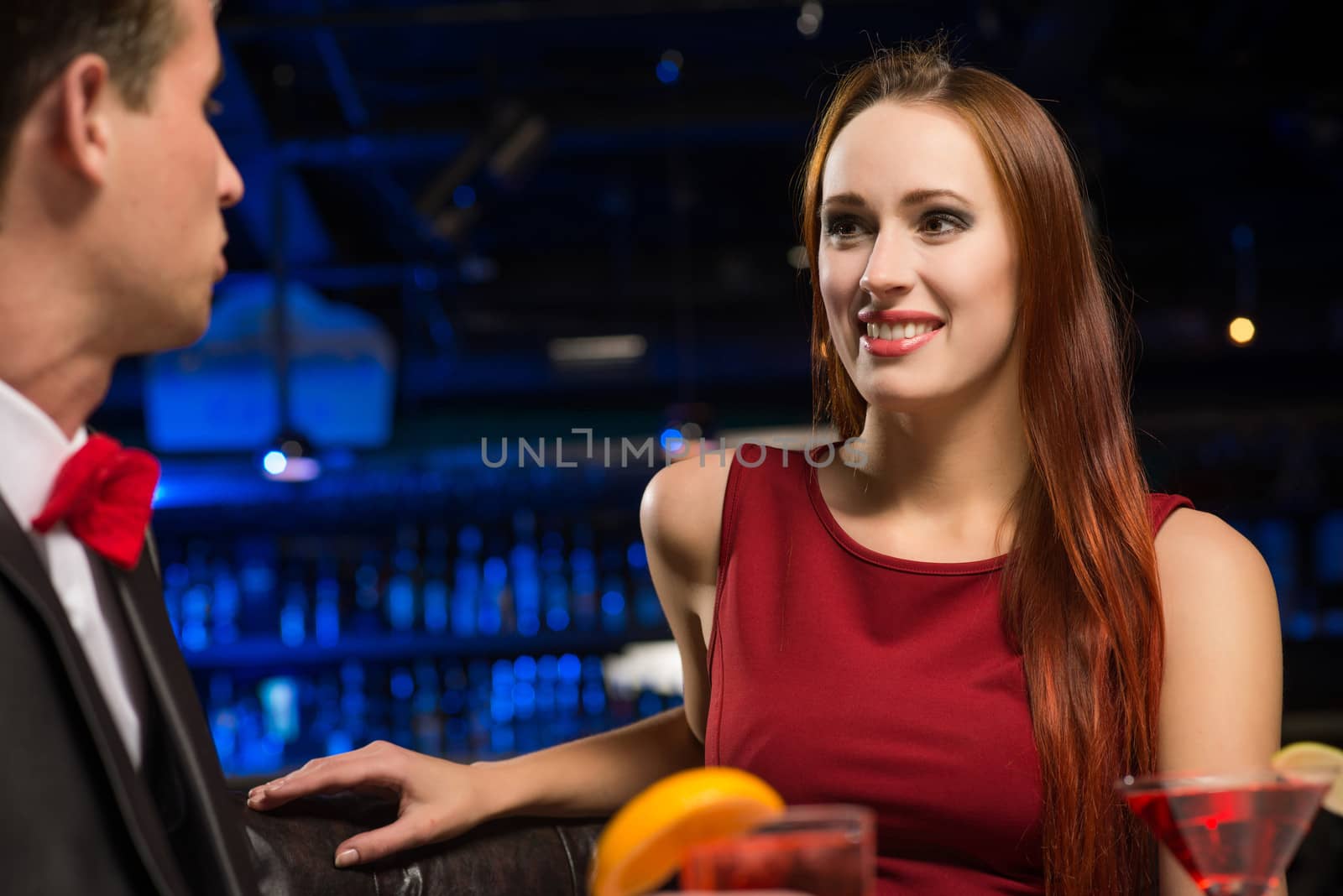 portrait of a woman in a nightclub, sitting on the couch and talking with man