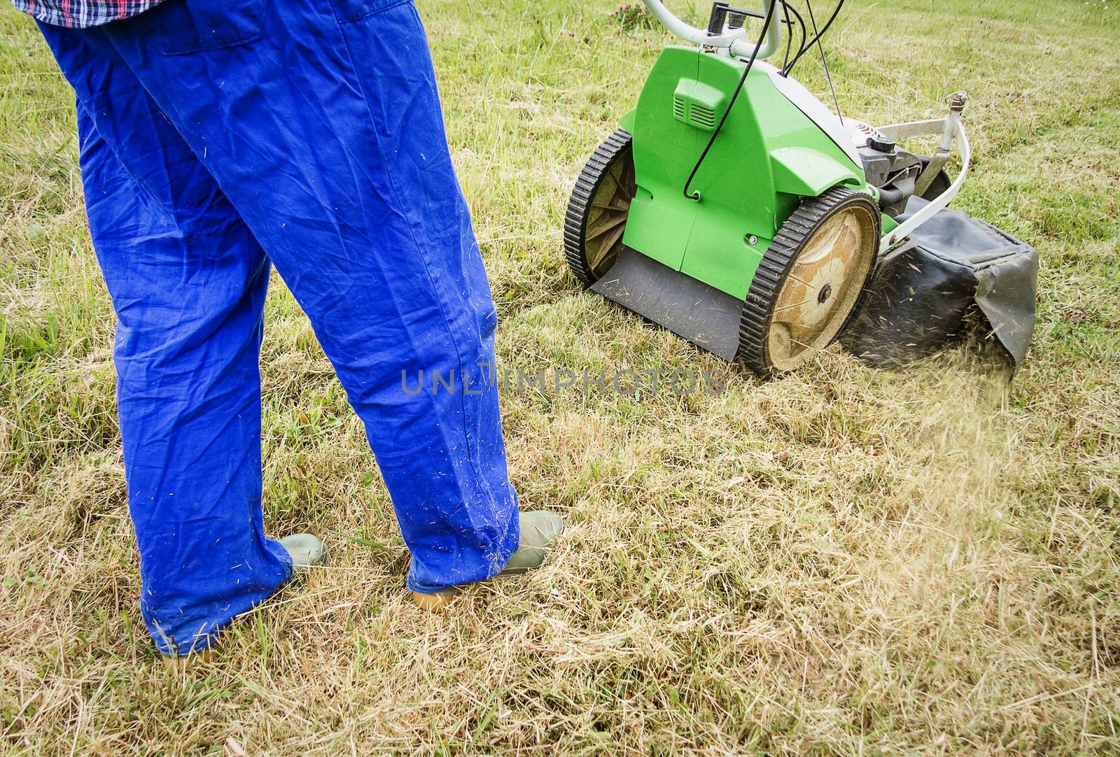 Young man mowing the lawn with a lawnmower machine