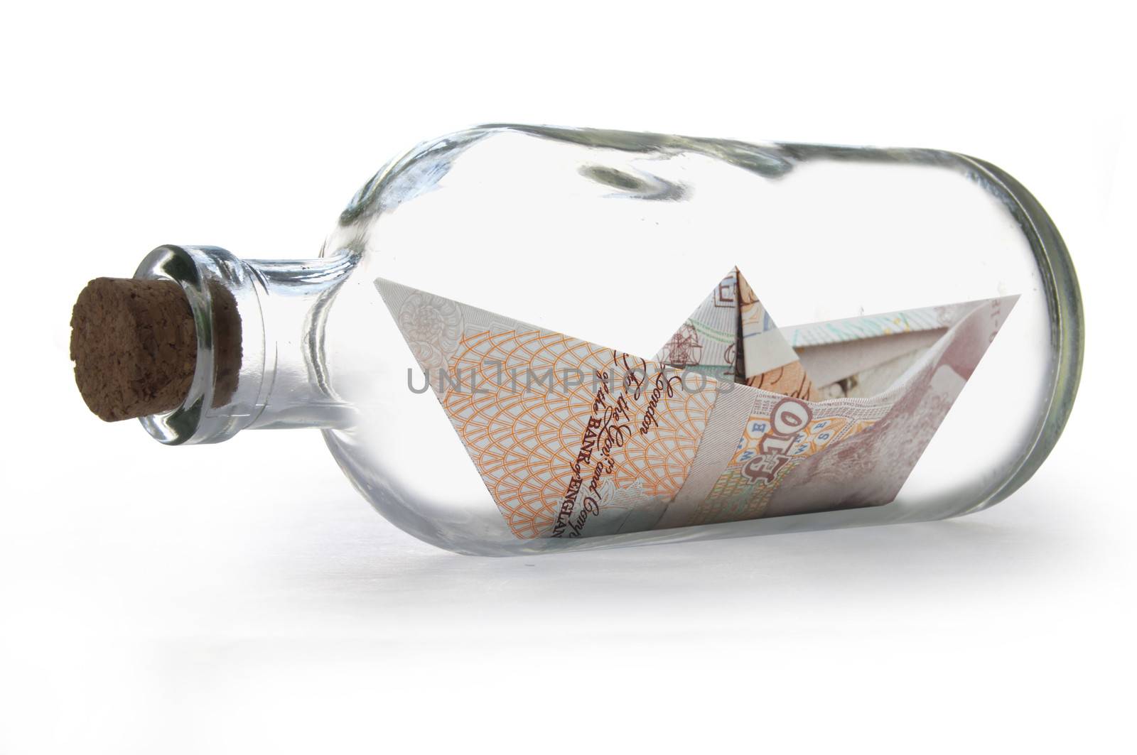 Paper boat made from British banknotes inside a message bottle 