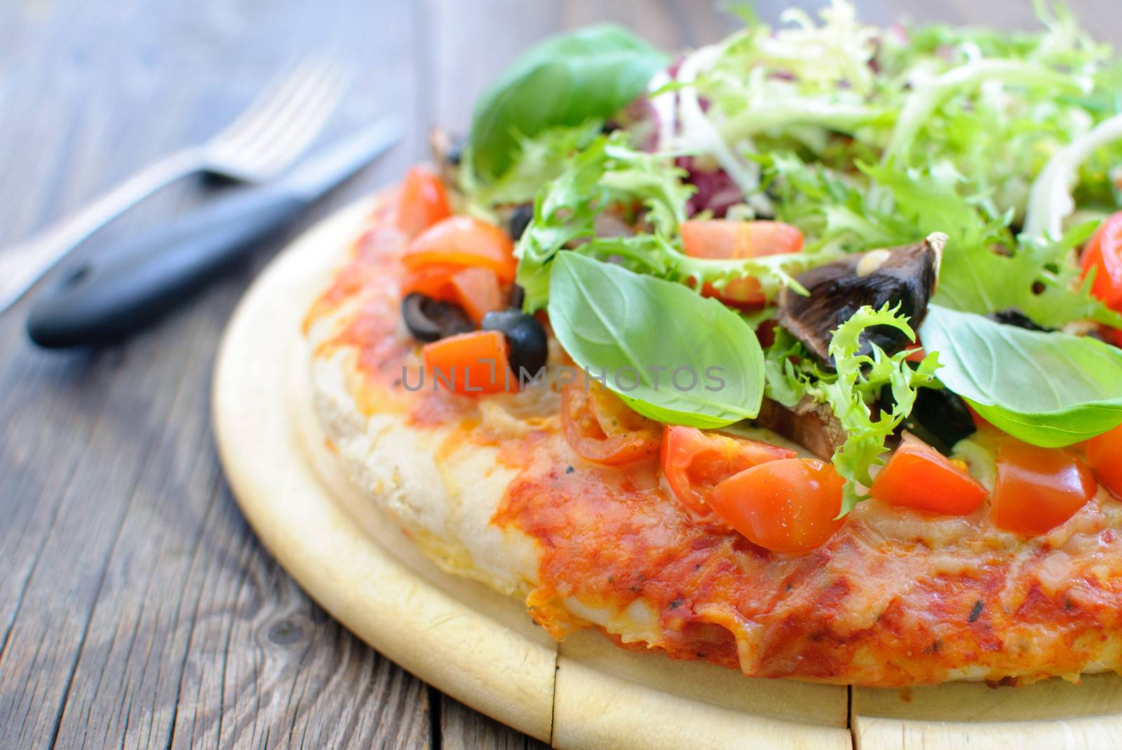 Close up of a deep pan pizza with basil, tomatoes and mushrooms