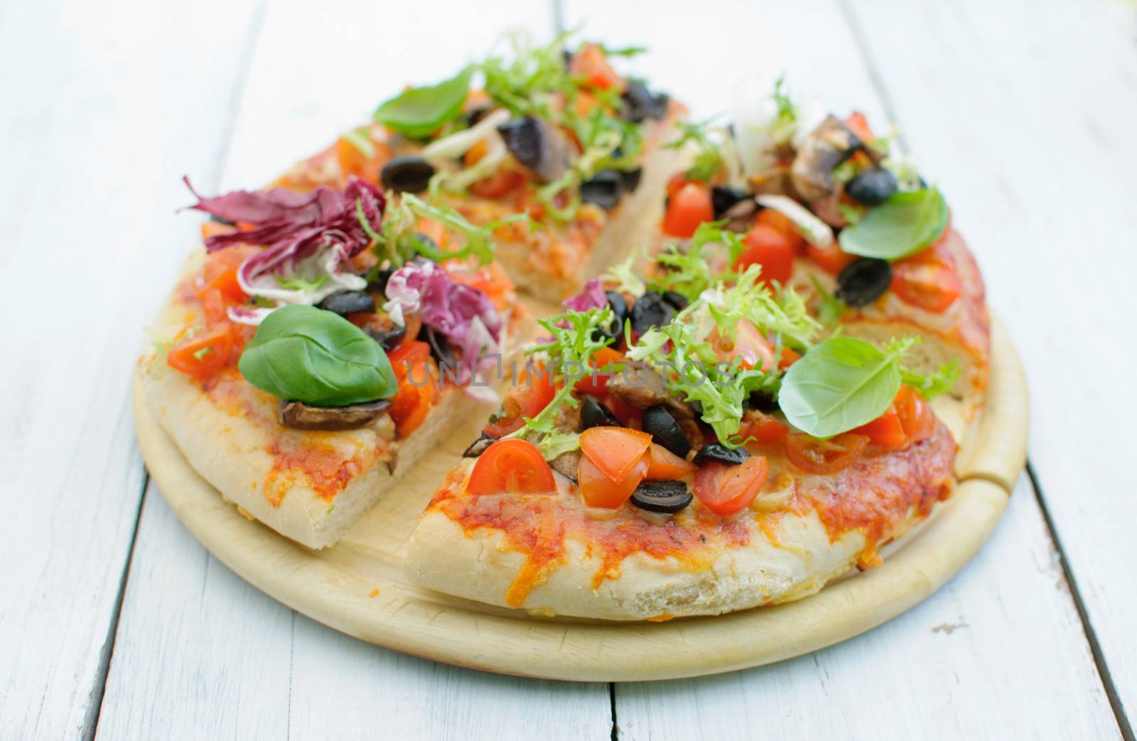 Gourmet pizza sliced into quarters on a chopping board 