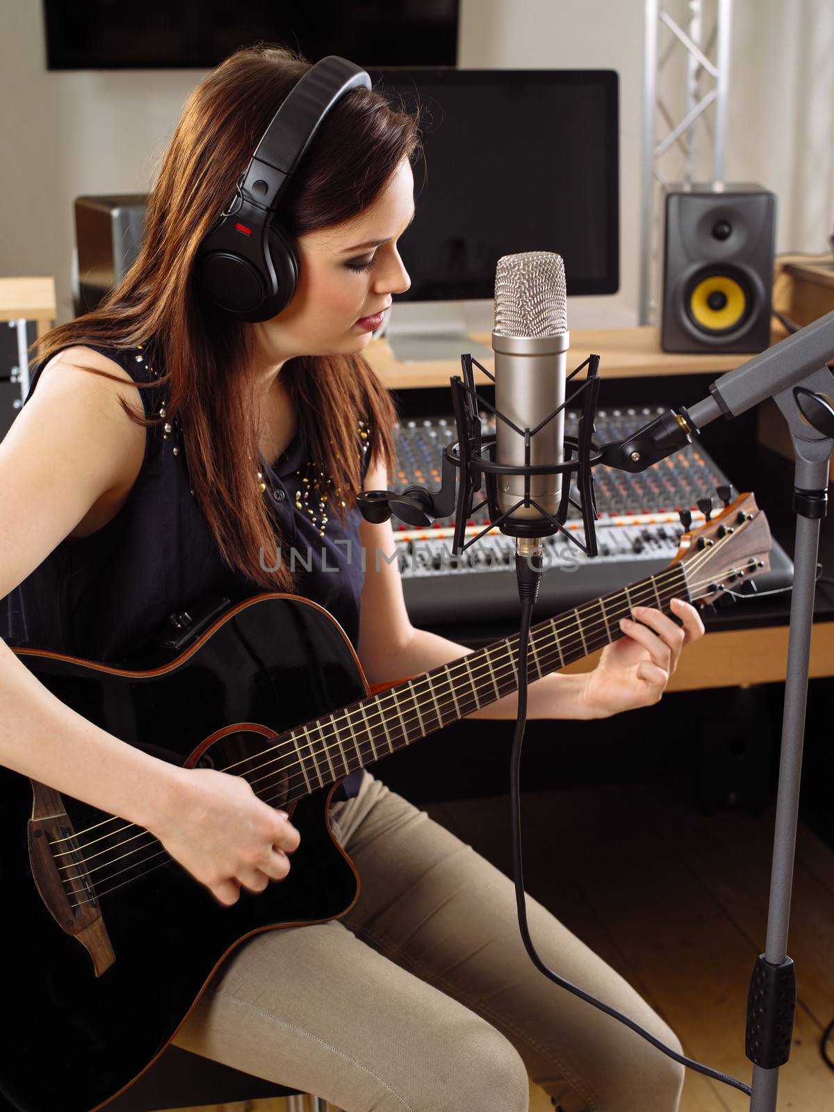 Woman with guitar in a recording studio by sumners