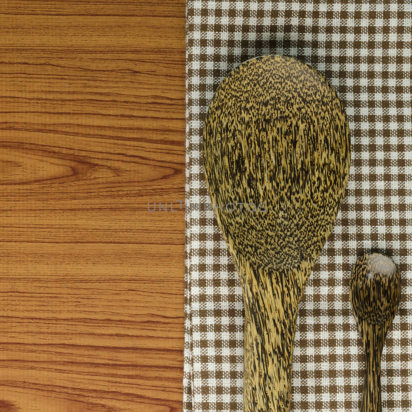 brown kitchen towel with spoon on wood background