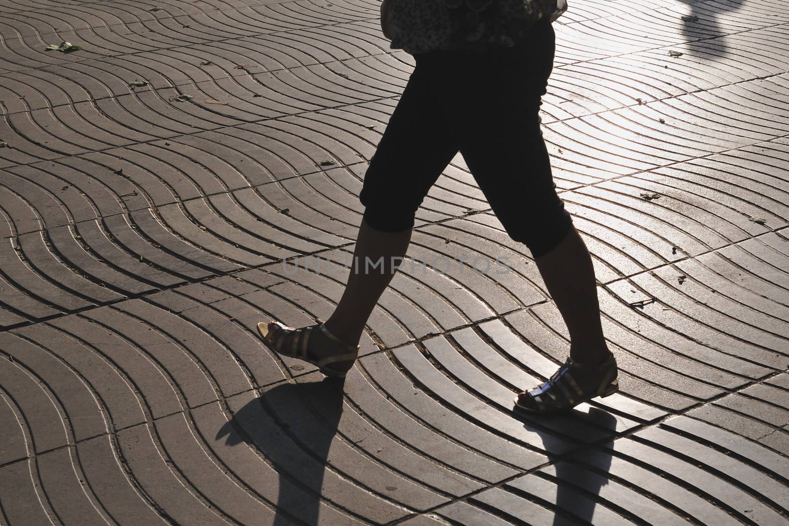 wave pattern tiled pavement of famous La Rambla street in Barcelona with walking woman silhouette