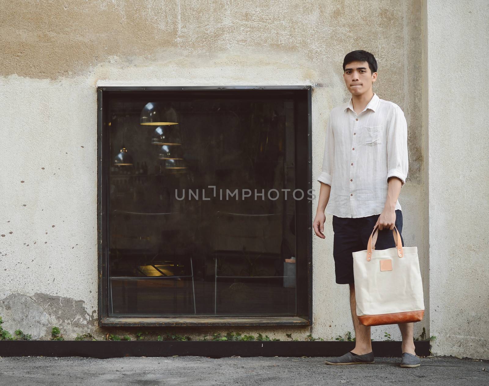 Man with canvas bag on grunge concrete background by siraanamwong
