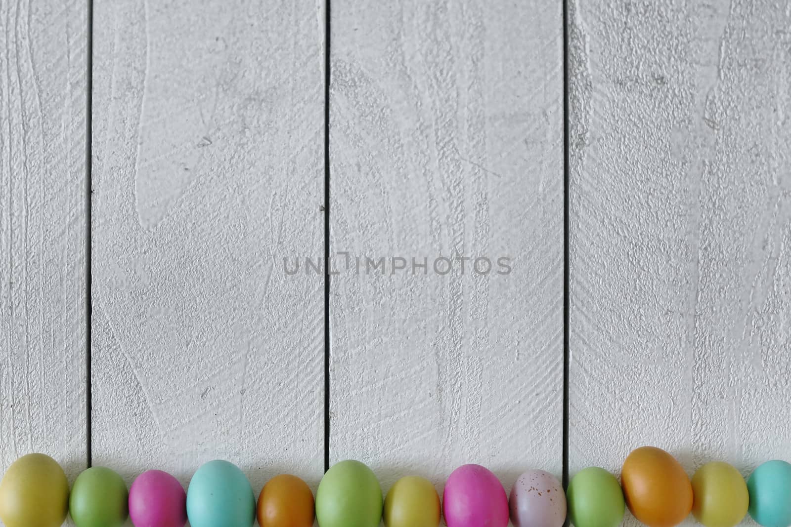 Spring or Easter Themed Background of Old Wood and Colored Eggs Lined Up