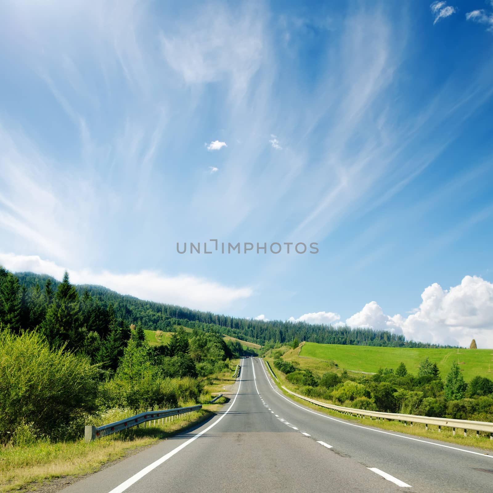 asphalt road to horizon in mountain and blue sky by mycola