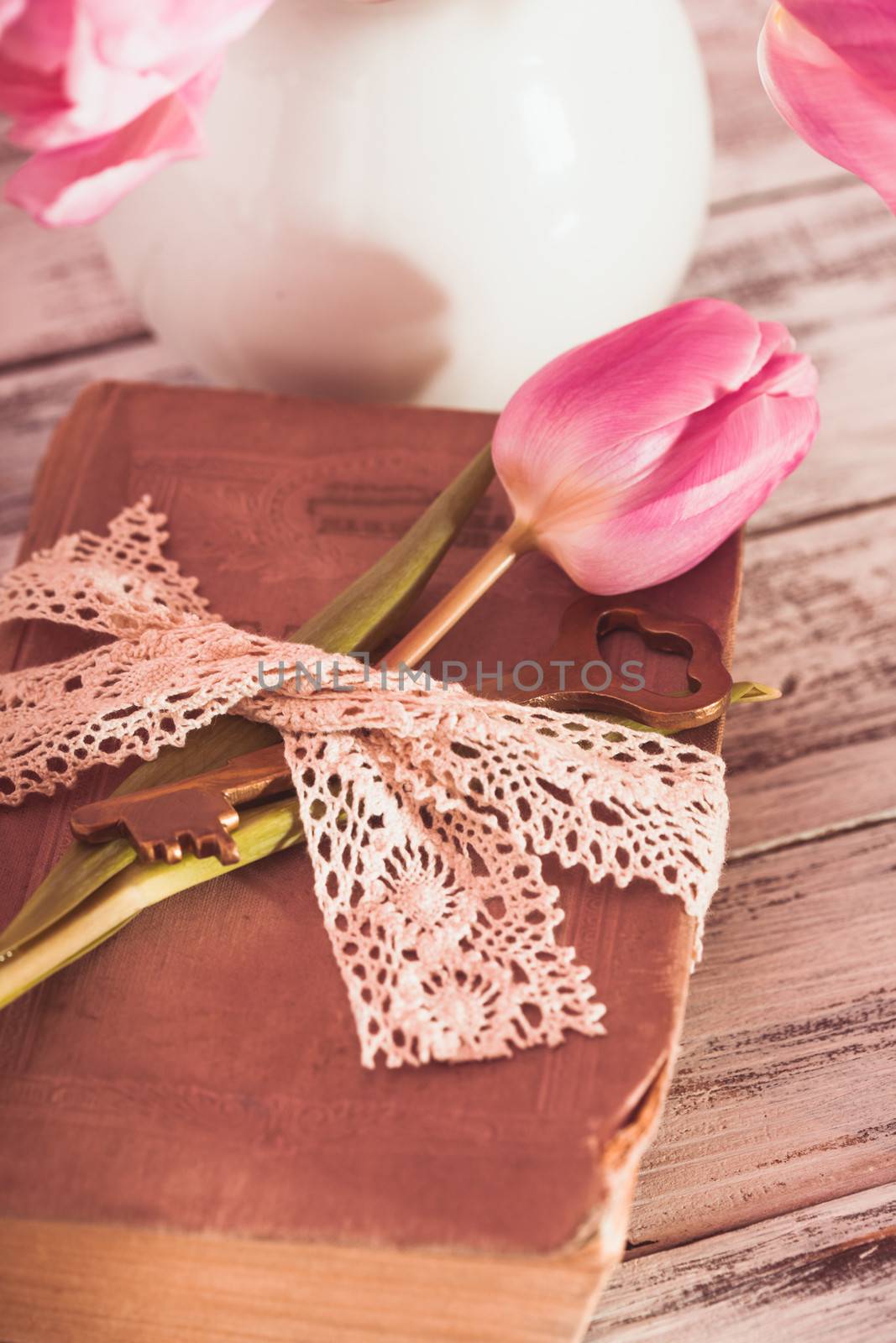 Memo still life with book, key, vintage lace and pink tulips