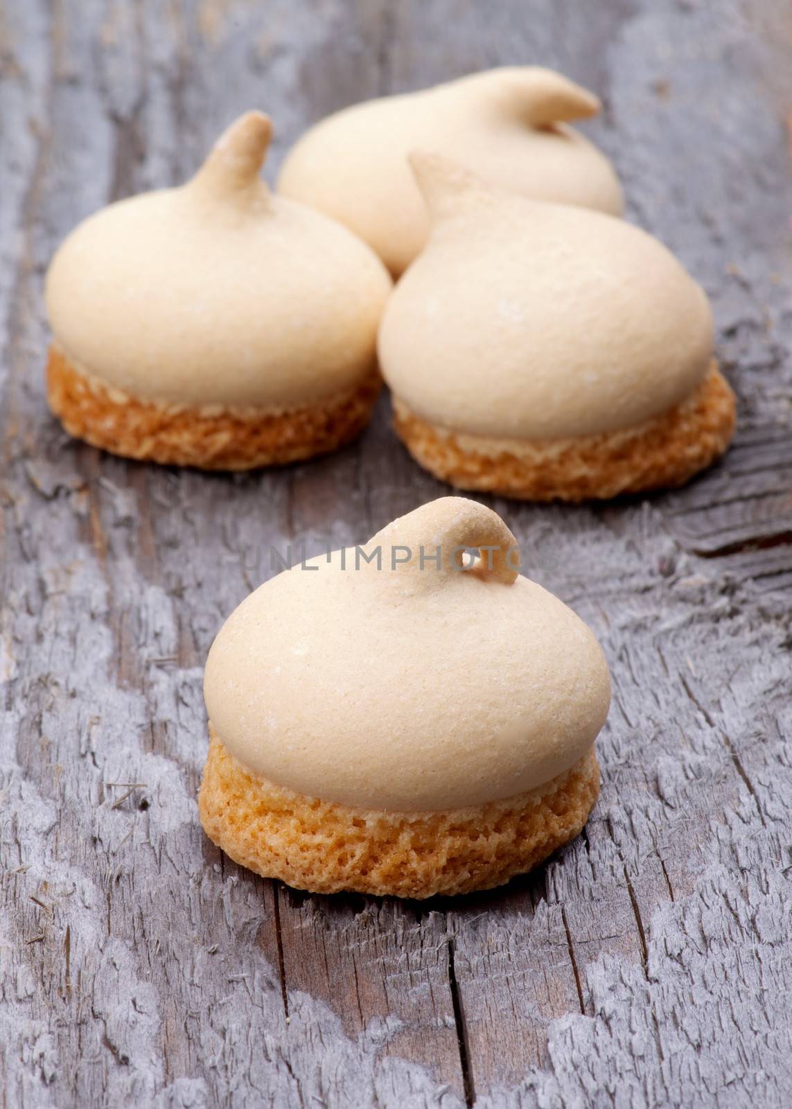 Arrangement of Swirled Meringue Topping with Biscuit Bottom isolated on Rustic Wooden background