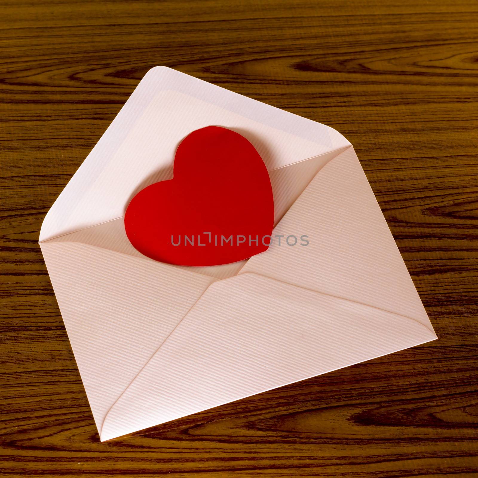 red heart with pink envelope on wooden background