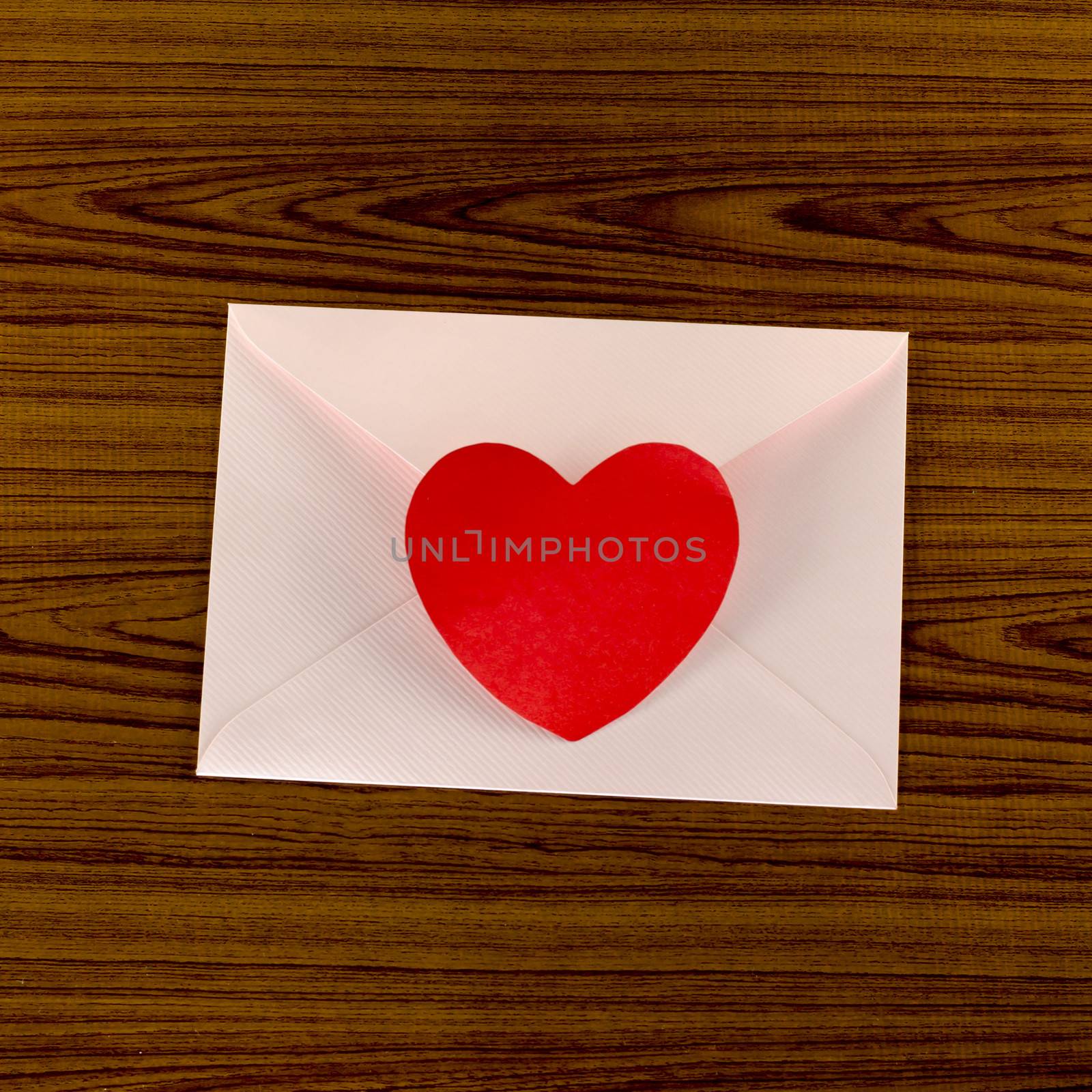 red heart with pink envelope on wooden background