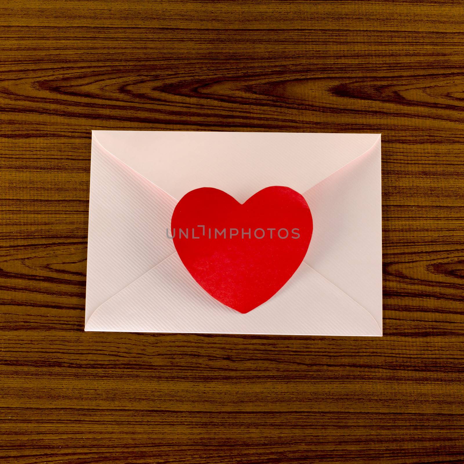 red heart with pink envelope on wooden background