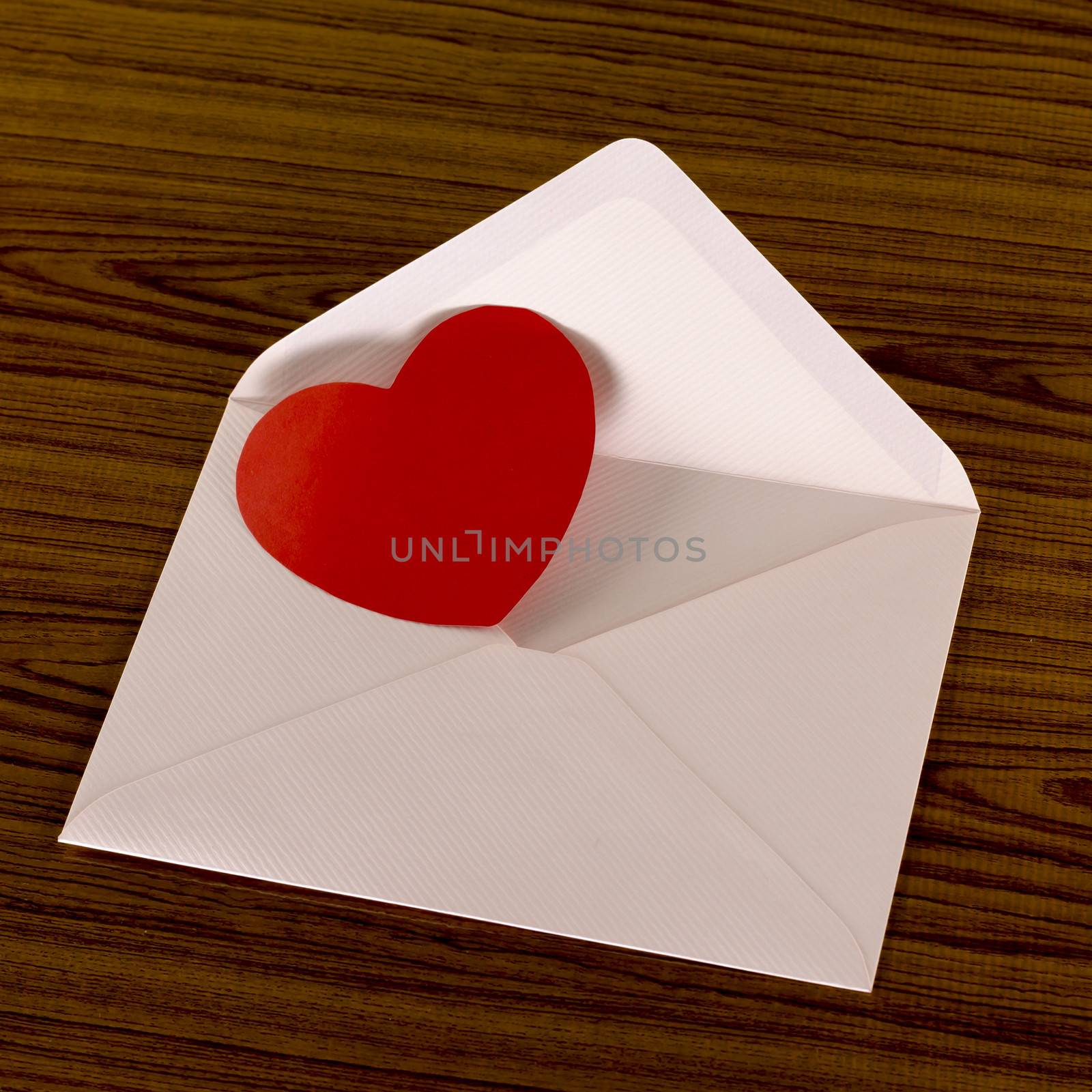 red heart with pink envelope on wooden background