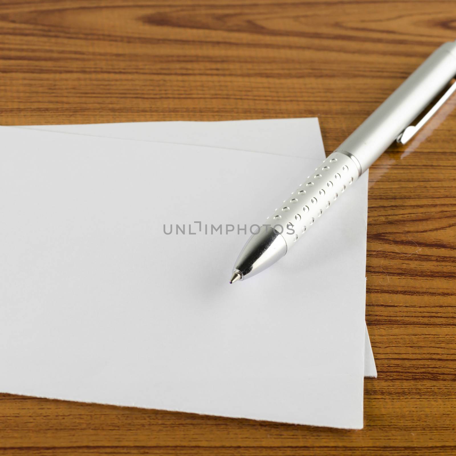 pen with white paper on wooden background