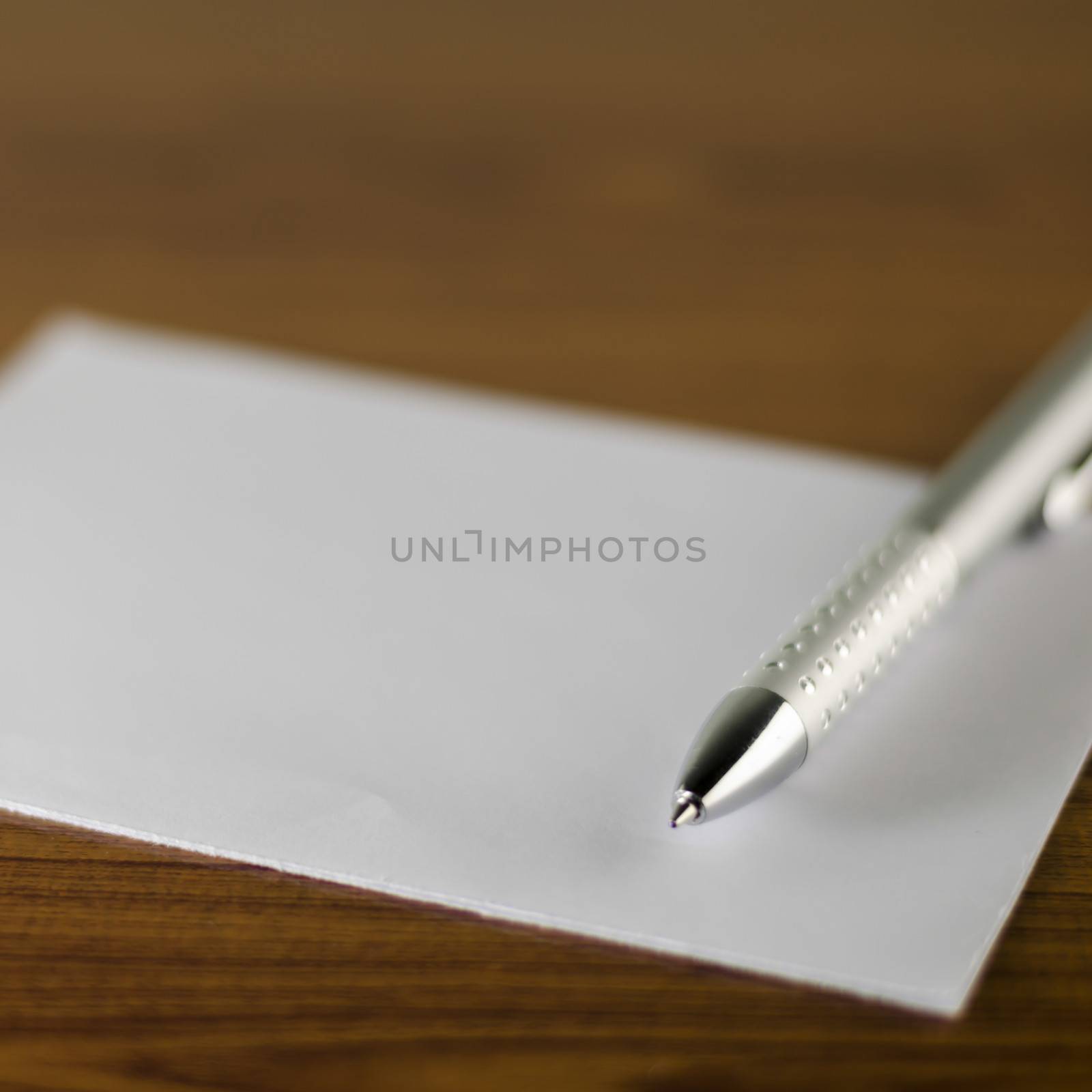 pen with white paper on wooden background