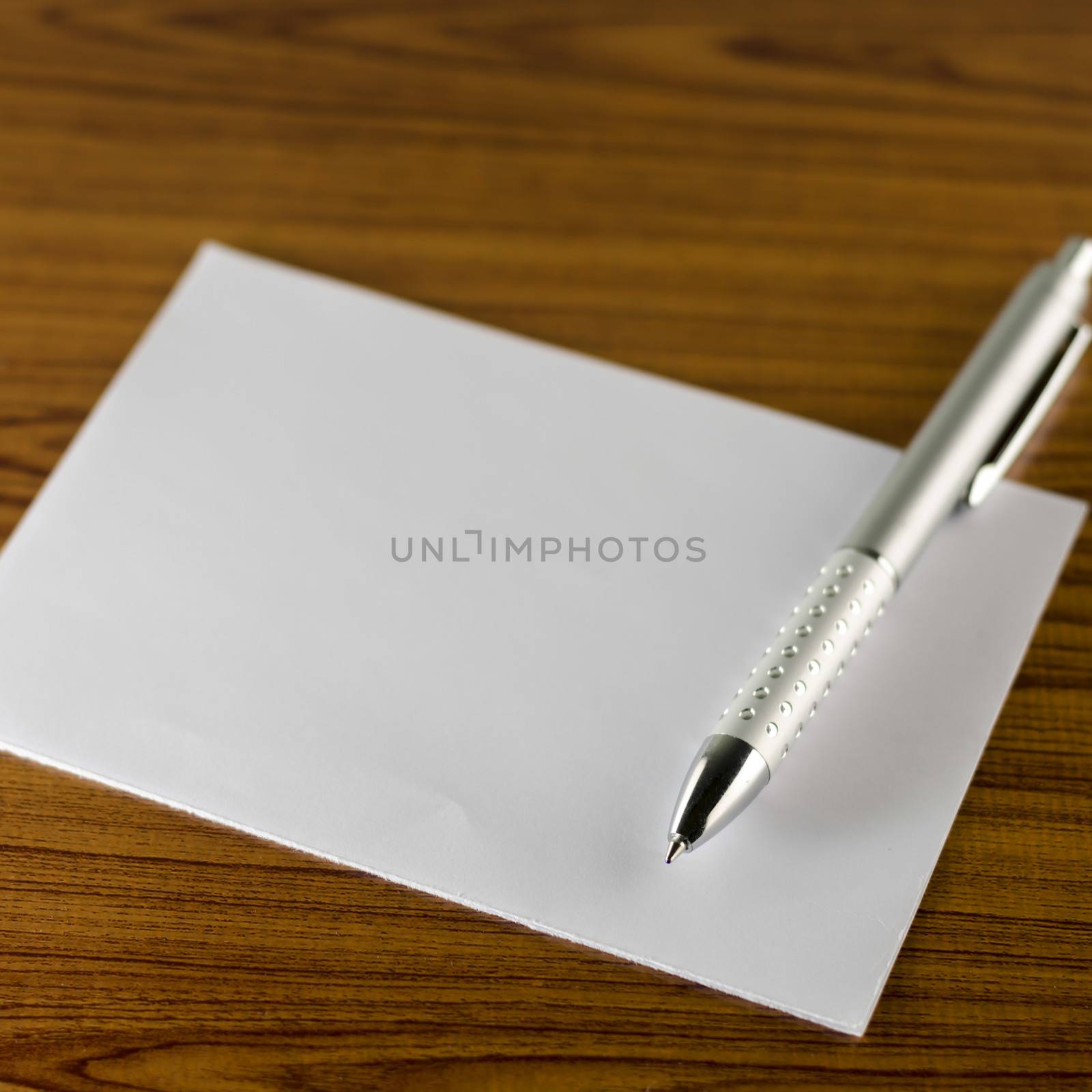 pen with white paper on wooden background