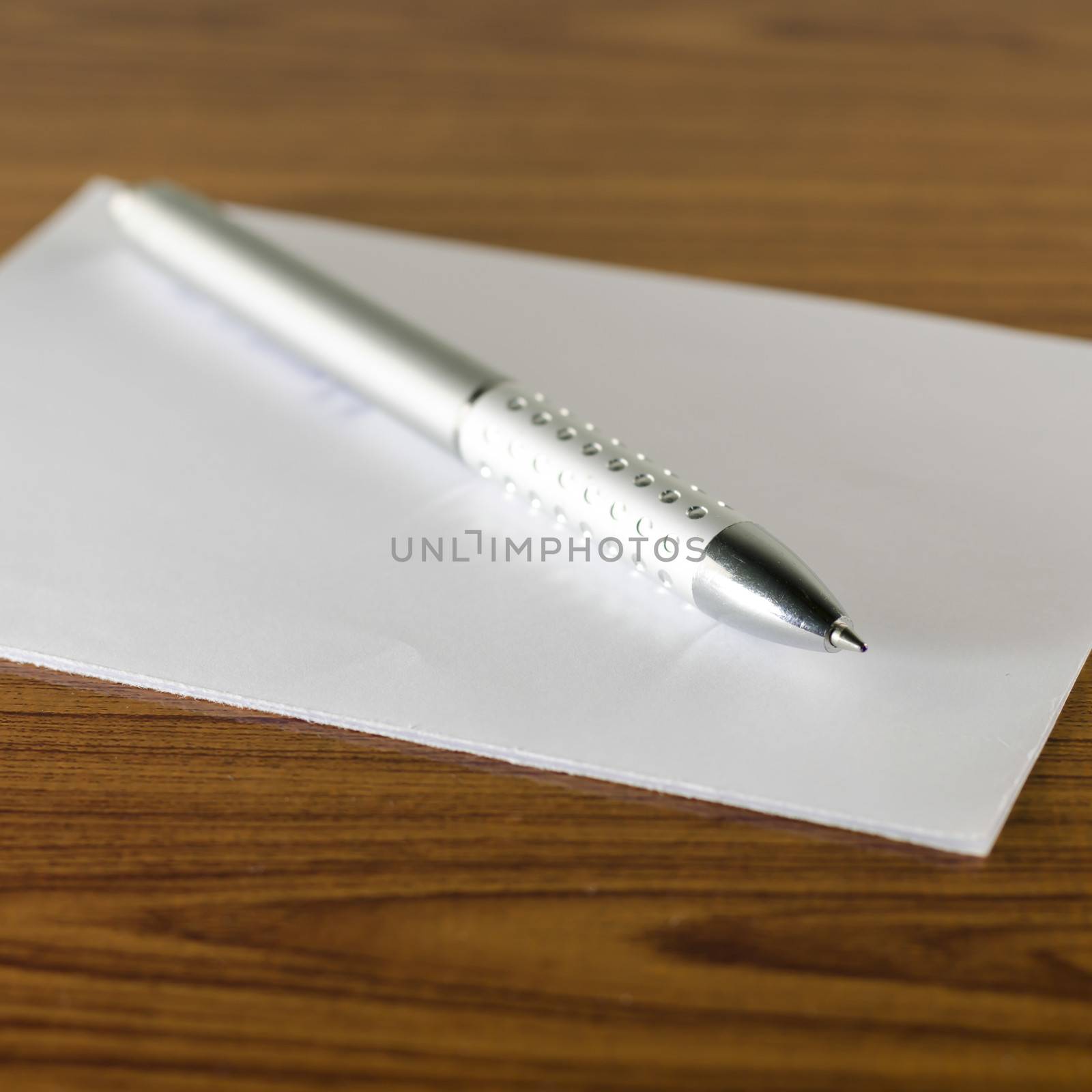 pen with white paper on wooden background