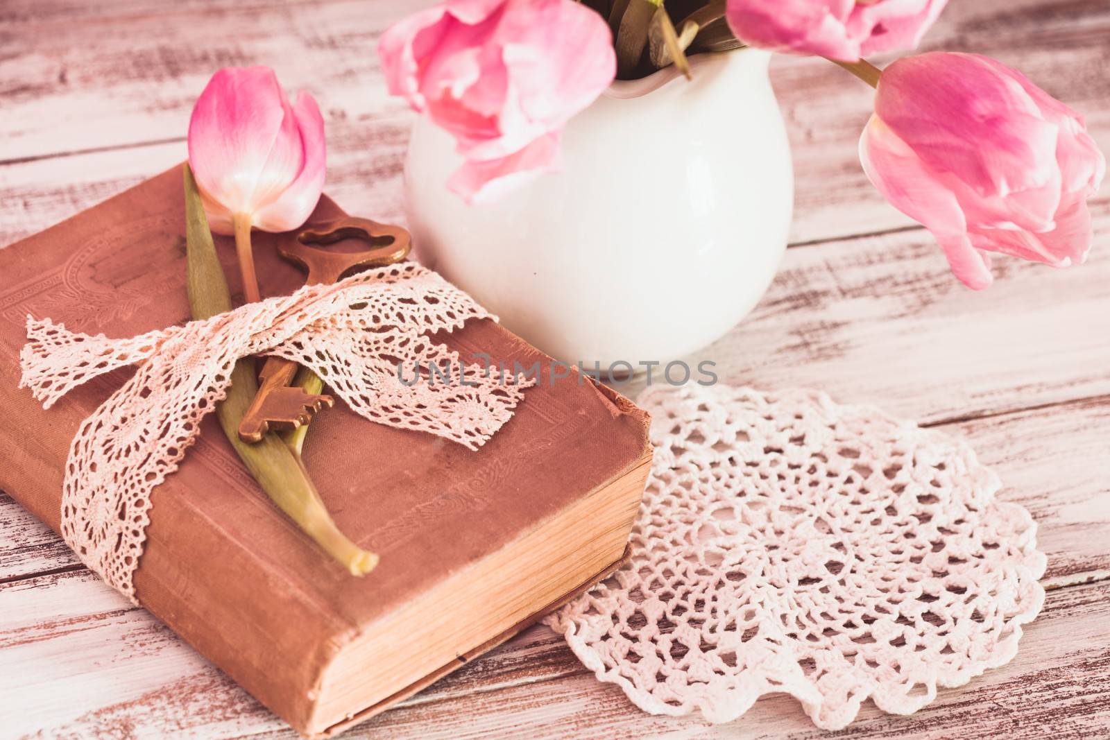 Memo still life with book, key, vintage lace and pink tulips