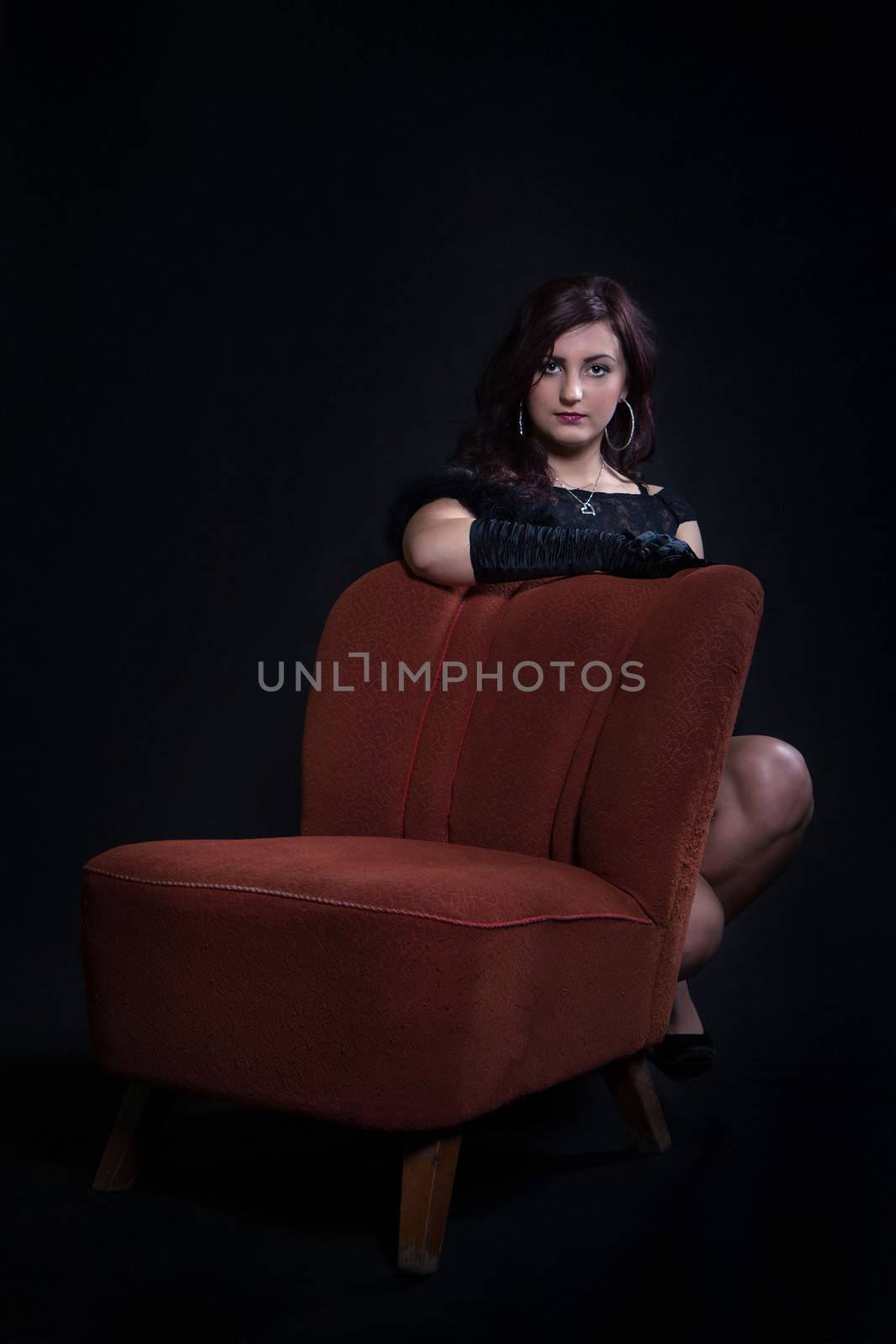Young woman in retro clothes sitting on old orange chair