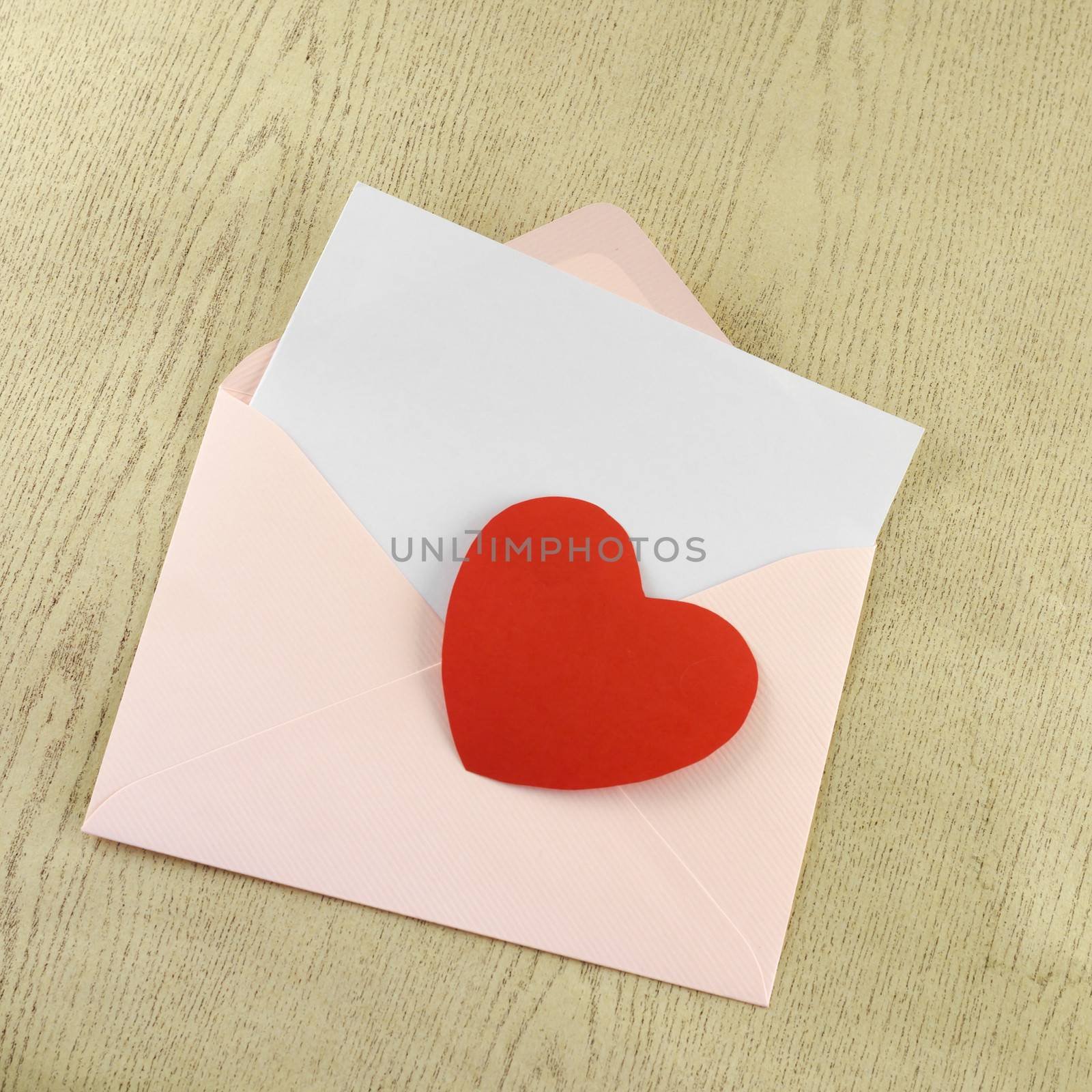 red heart with pink envelope on wooden background
