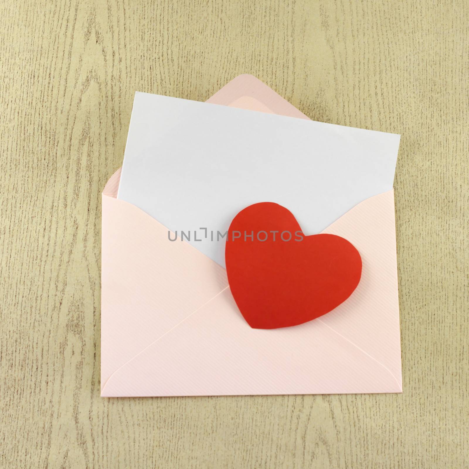 red heart with pink envelope on wooden background