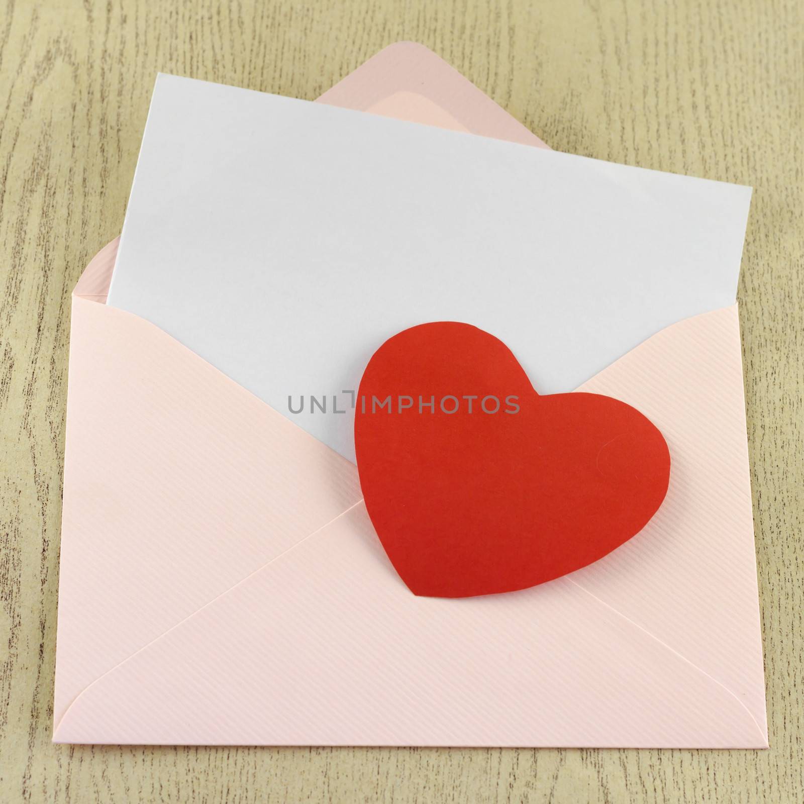 red heart with pink envelope on wooden background