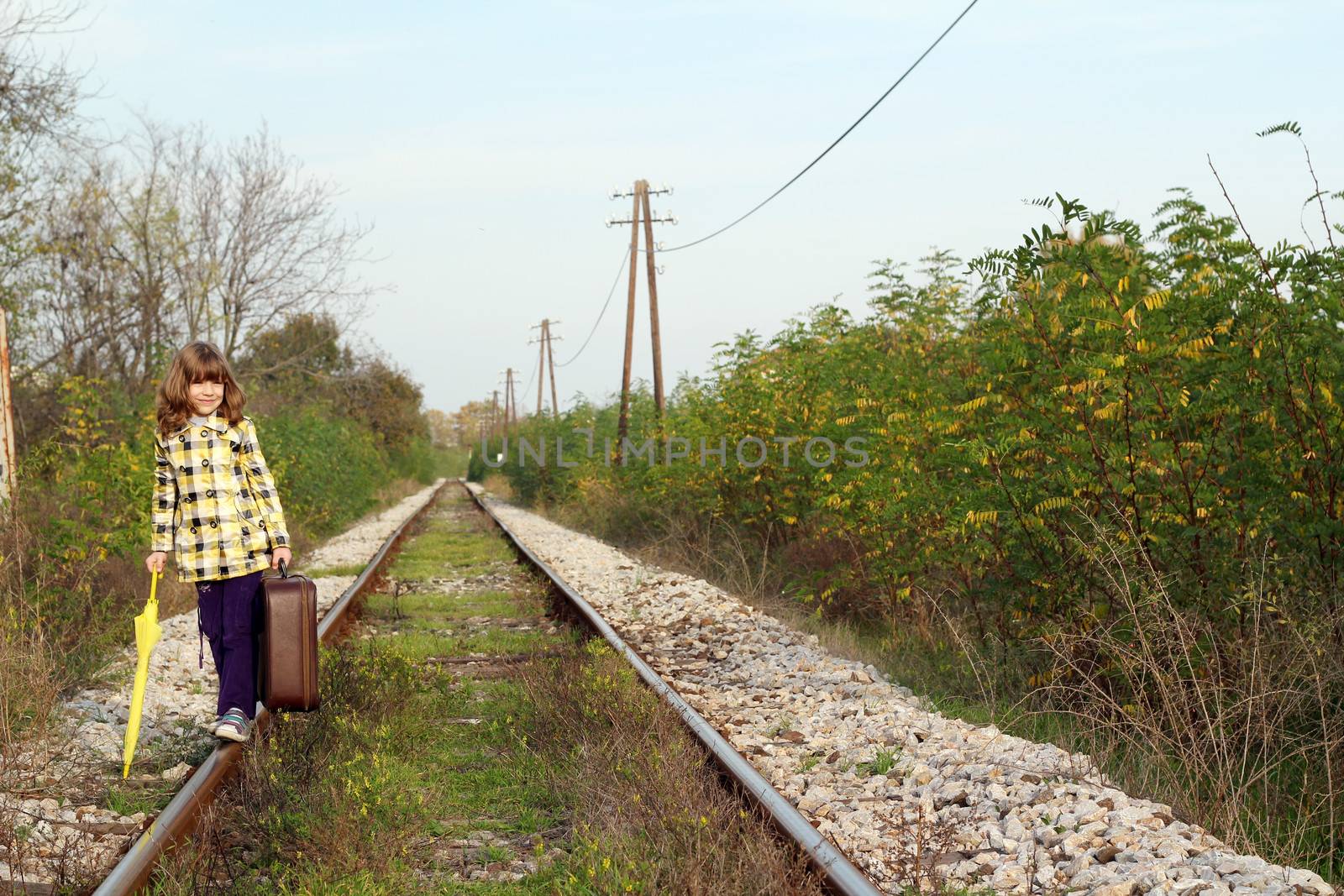 beautiful little girl with suitcase on railroad by goce